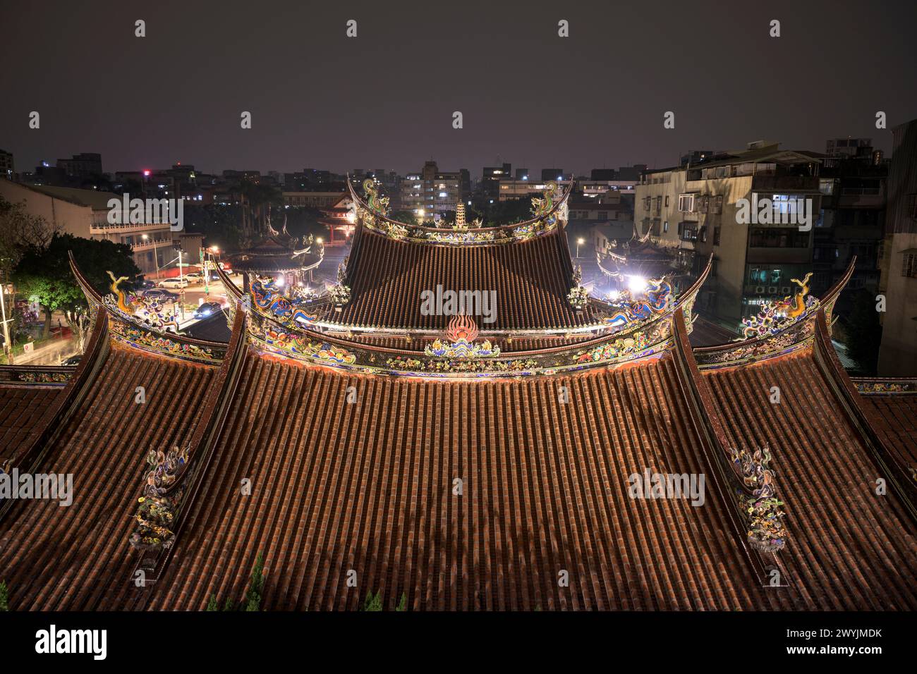 Un intricato tetto del tempio illuminato di notte, che mostra la tradizionale architettura asiatica e il patrimonio culturale Foto Stock