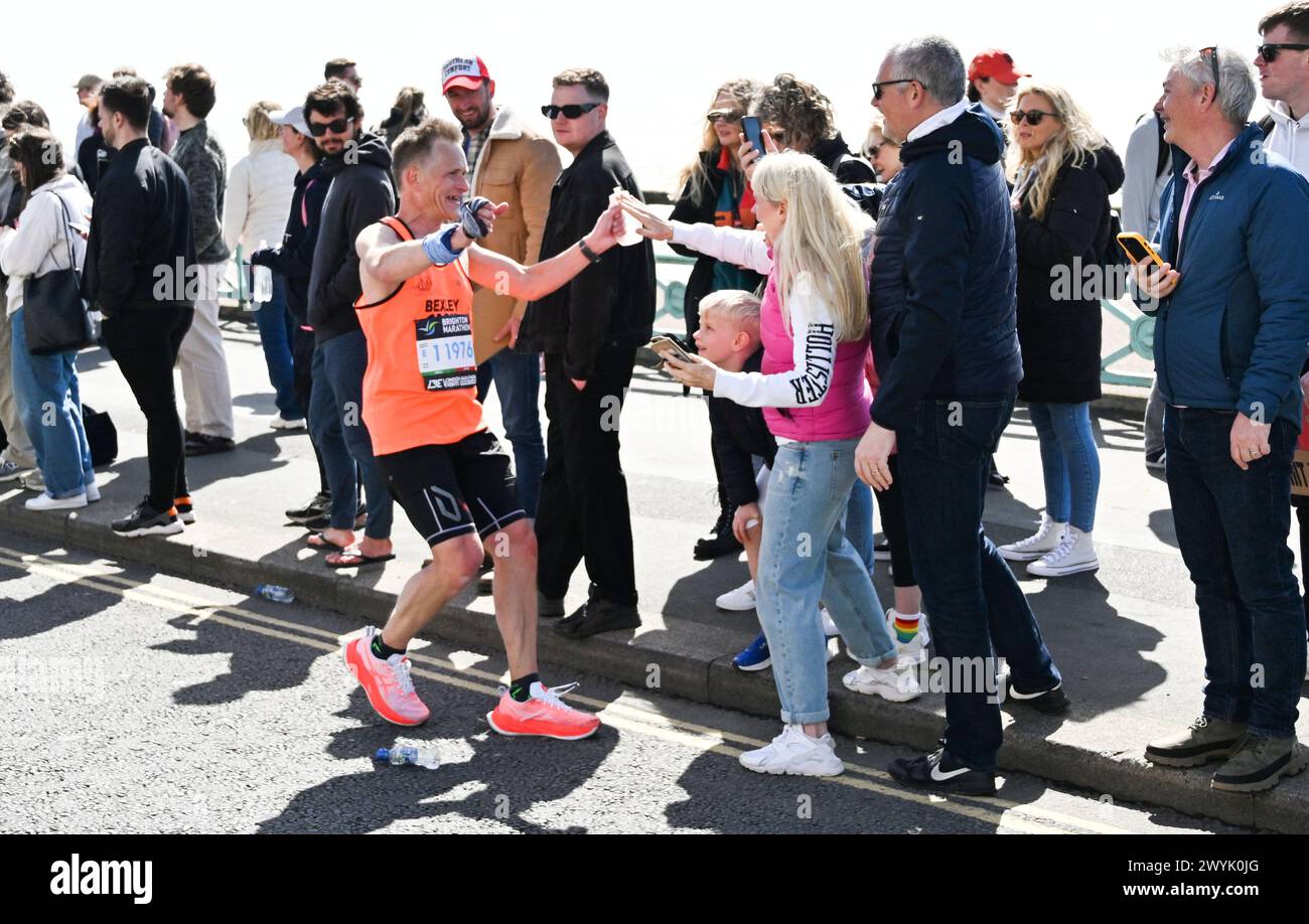 Brighton Regno Unito 7 aprile 2024 - questo corridore sta per ricevere un abbraccio mentre migliaia di persone prendono parte alla Maratona di Brighton in una giornata luminosa soleggiata ma ventosa: Credit Simon Dack / Alamy Live News Foto Stock