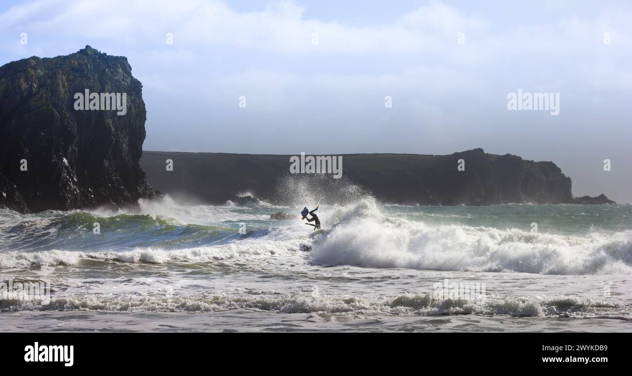 Wave board o body board navigando in enormi breakers a Kynance Cove, Cornovaglia. Spazzare via a forma di simbolo Manx. Triskelion. Affrontare le onde Foto Stock