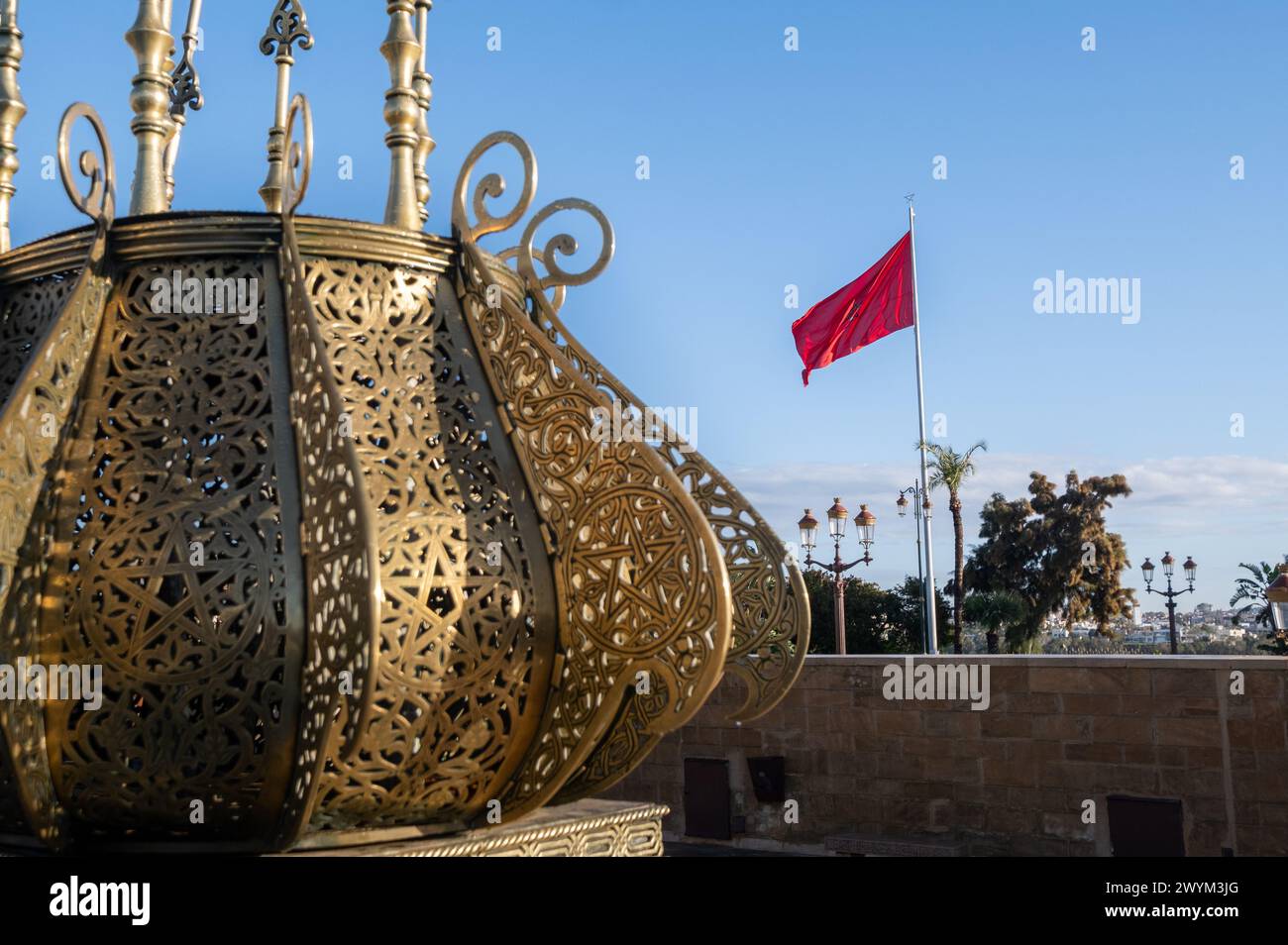 Dettaglio degli elementi decorativi del Mausoleo reale del complesso di Mohammed V a Rabat, in Marocco, con la bandiera marocchina che sventolava sullo sfondo su una Foto Stock