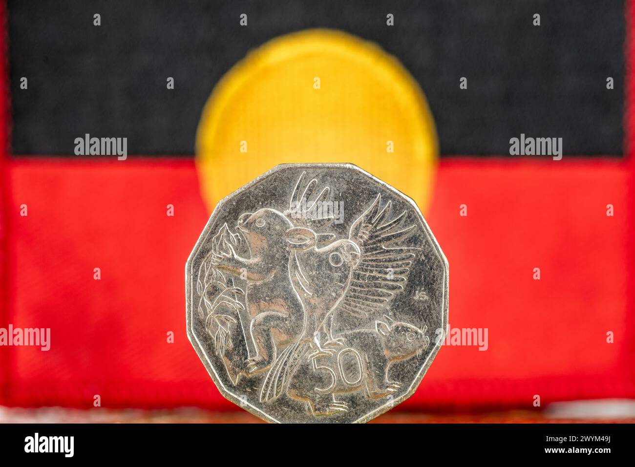 Bandiera aborigena con moneta da 50 centesimi australiani, concetto, situazione degli indigeni dell'Australia, primo piano Foto Stock