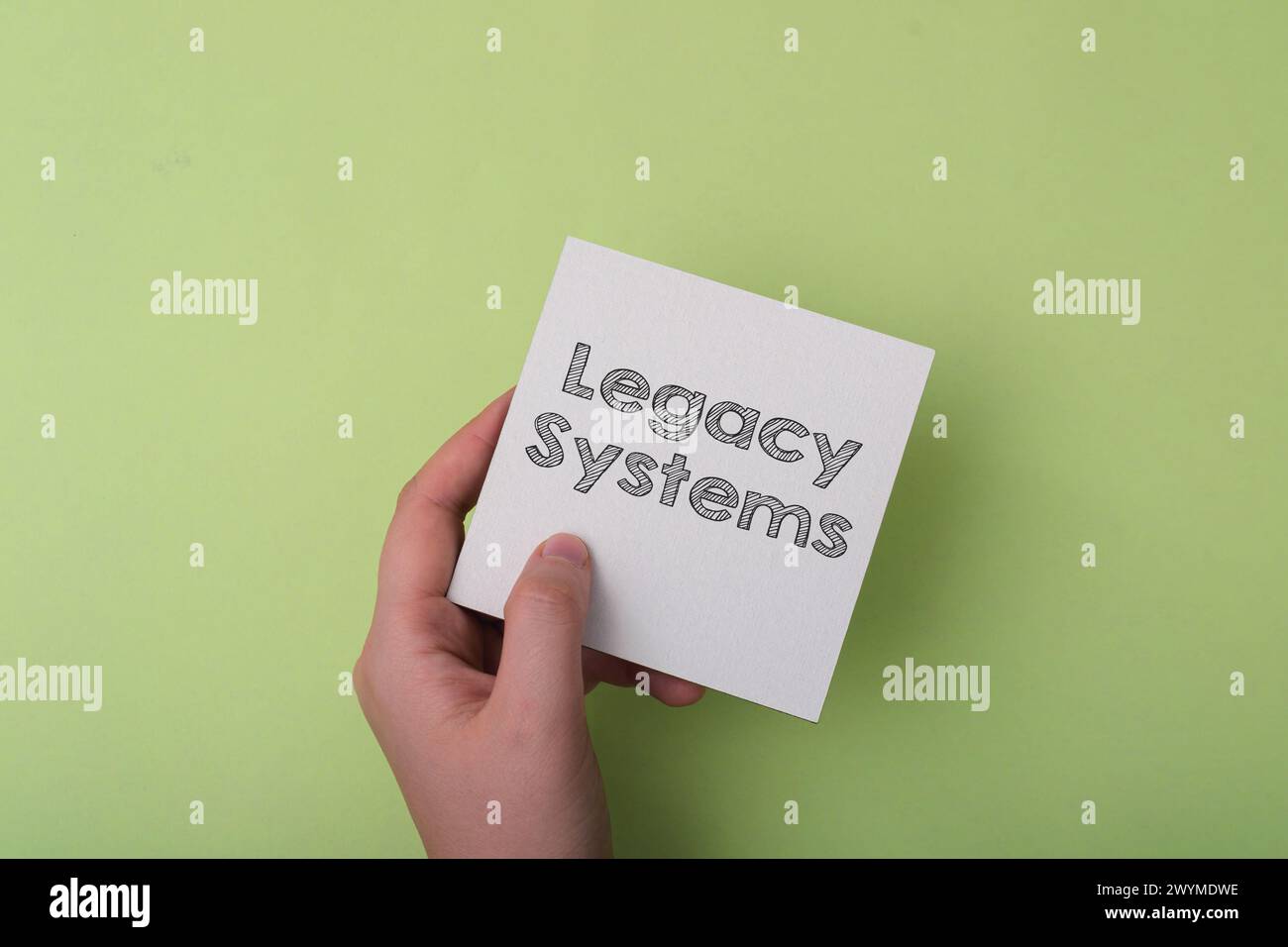 Una mano che regge un pezzo di carta con la parola sistemi legacy scritta sopra. Concetto di tramandare conoscenze e tradizioni da una generazione all'altra Foto Stock