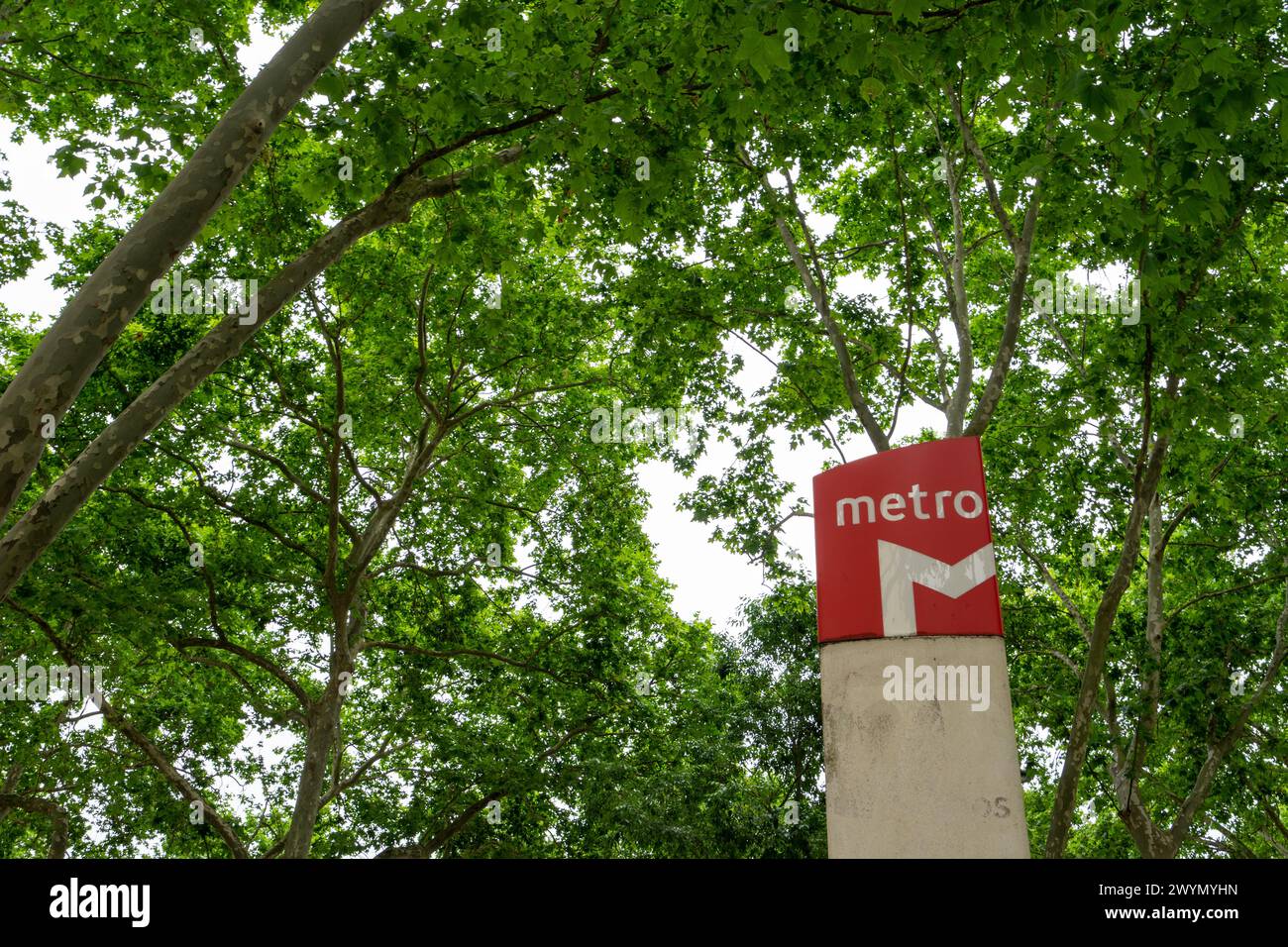 Cubo rosso che identifica l'ingresso alla stazione della metropolitana di Lisbona. sfondo verde. Foto Stock