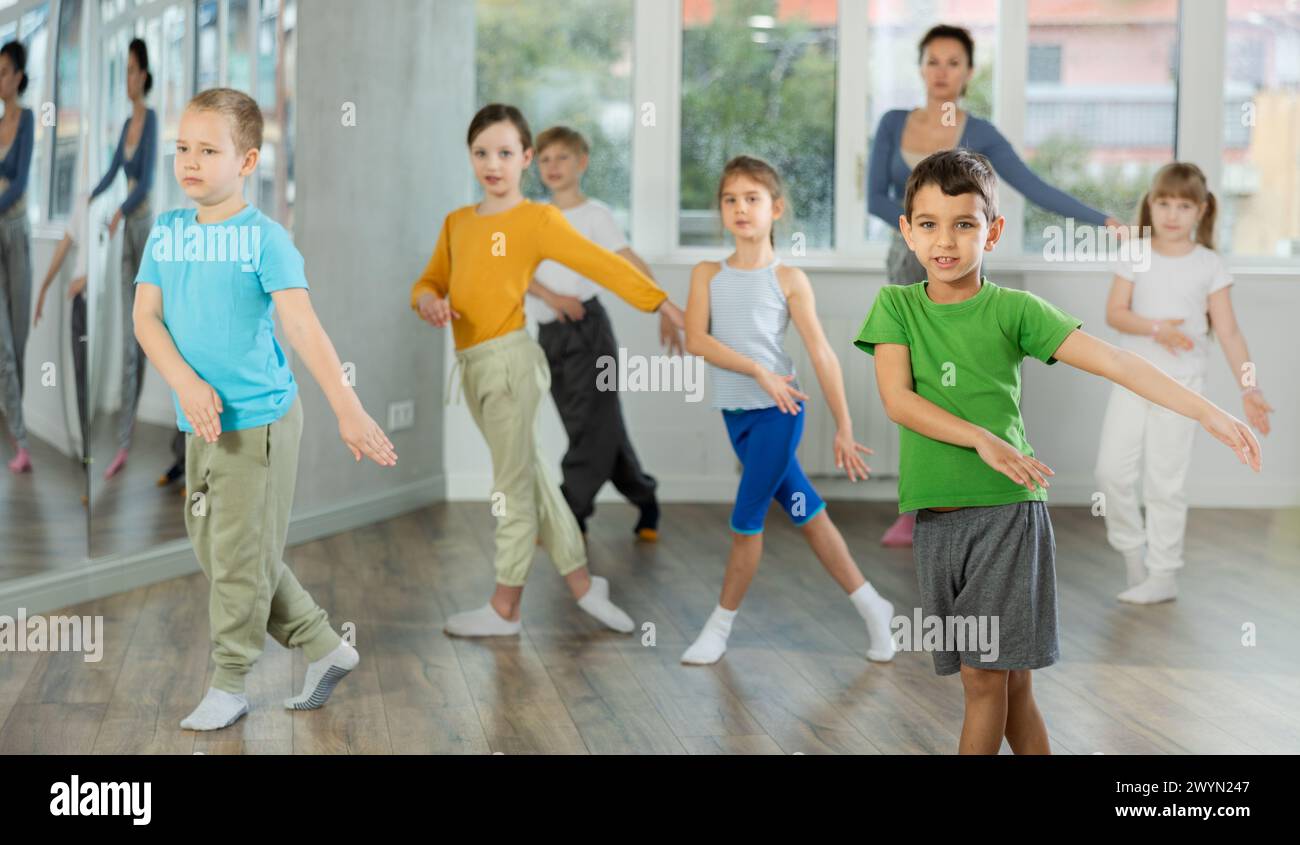 I bambini che allenano la danza moderna si muovono insieme in studio sotto la guida di un insegnante Foto Stock