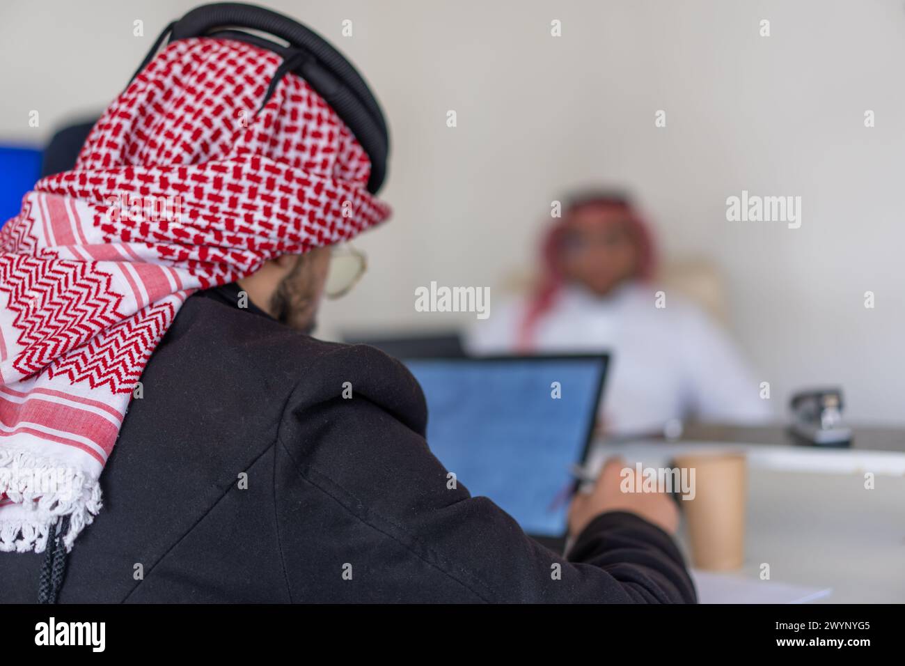Gli uomini arabi sono nel bel mezzo del lavoro in ufficio che si aiutano a vicenda Foto Stock