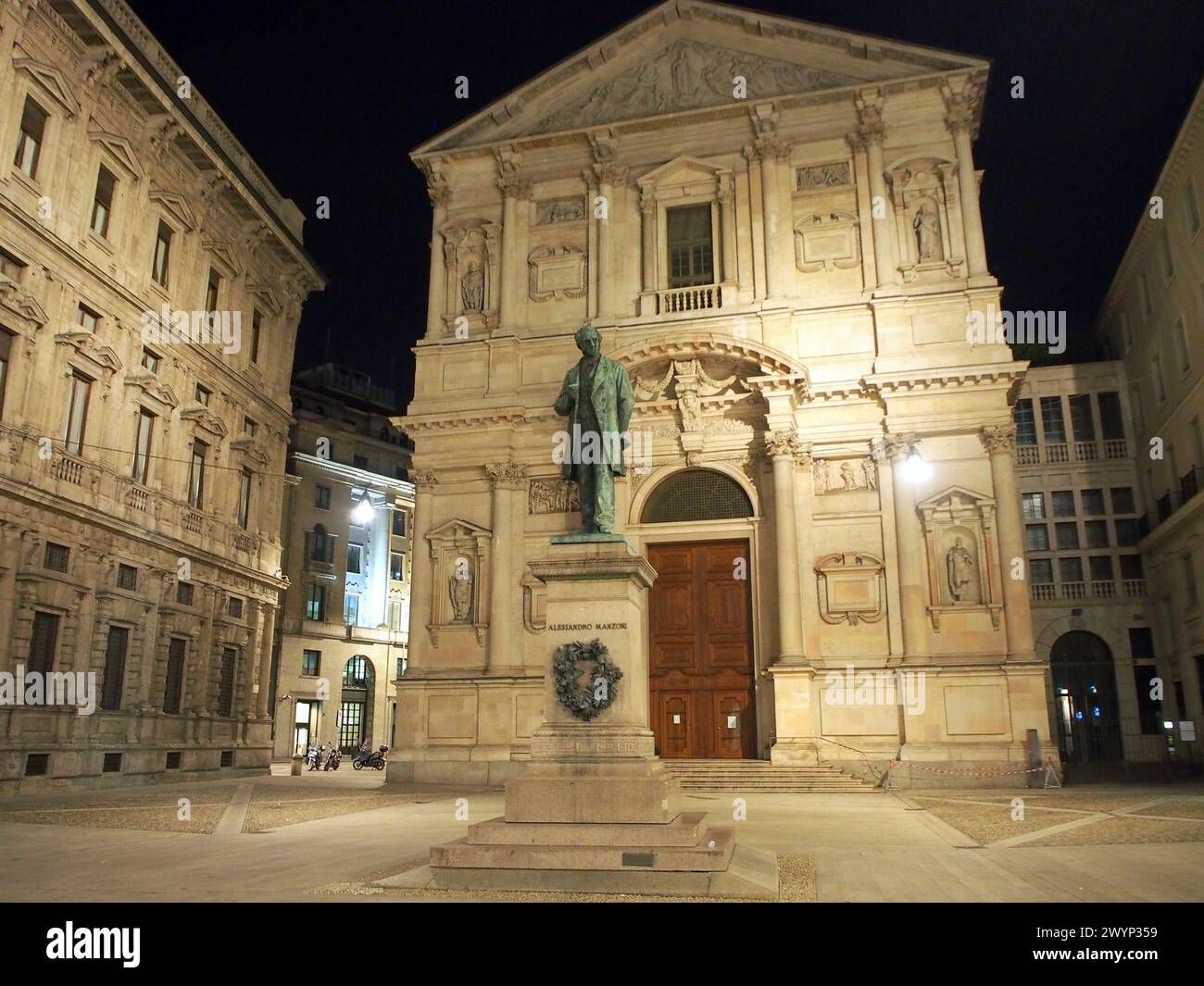 Chiesa di San fedele, illuminata di notte, statua di Alessandro Manzoni in primo piano, Milano, Italia Foto Stock