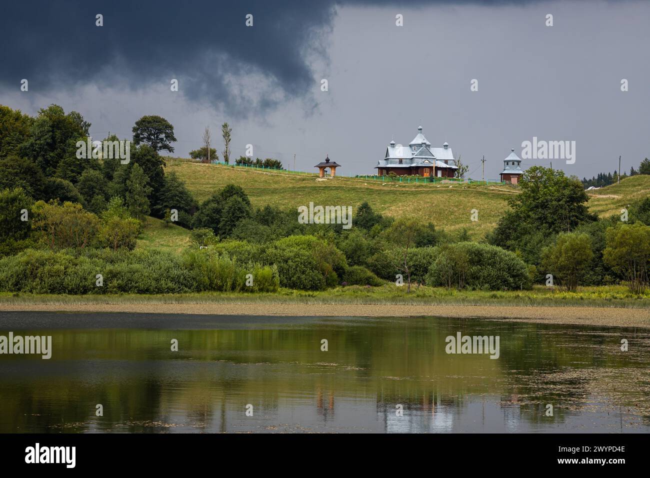 Nuvole tempesta, cielo minaccioso, collina e chiesa, alberi verdi prima della pioggia. Foto Stock
