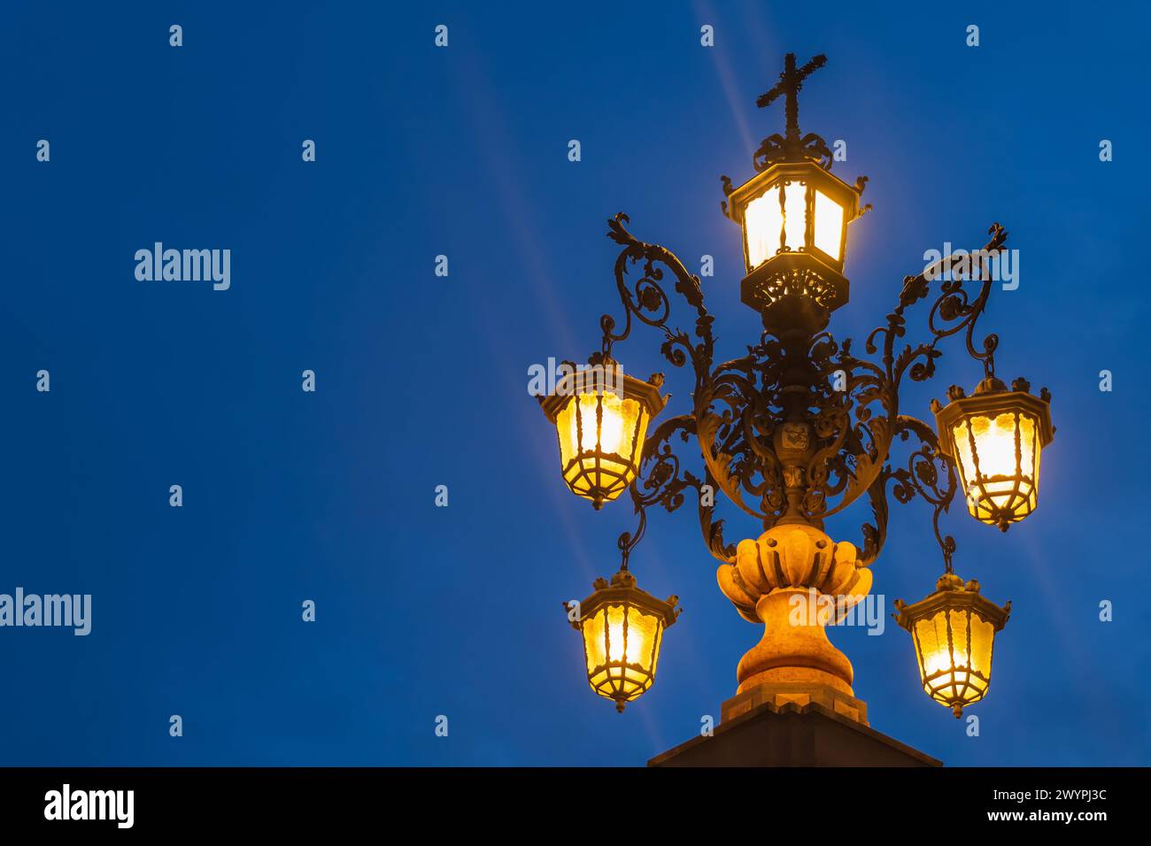 Lampada ornata della fontana Fuente de la Farola illuminata di notte, isolata contro il cielo serale a Siviglia, Andalusia, Spagna. Foto Stock