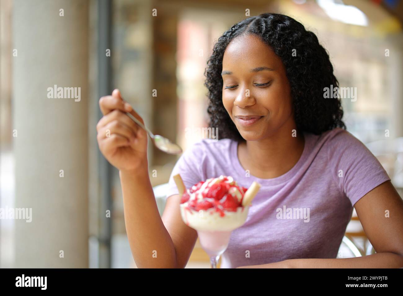 Donna nera che mangia fragole in una terrazza del ristorante Foto Stock