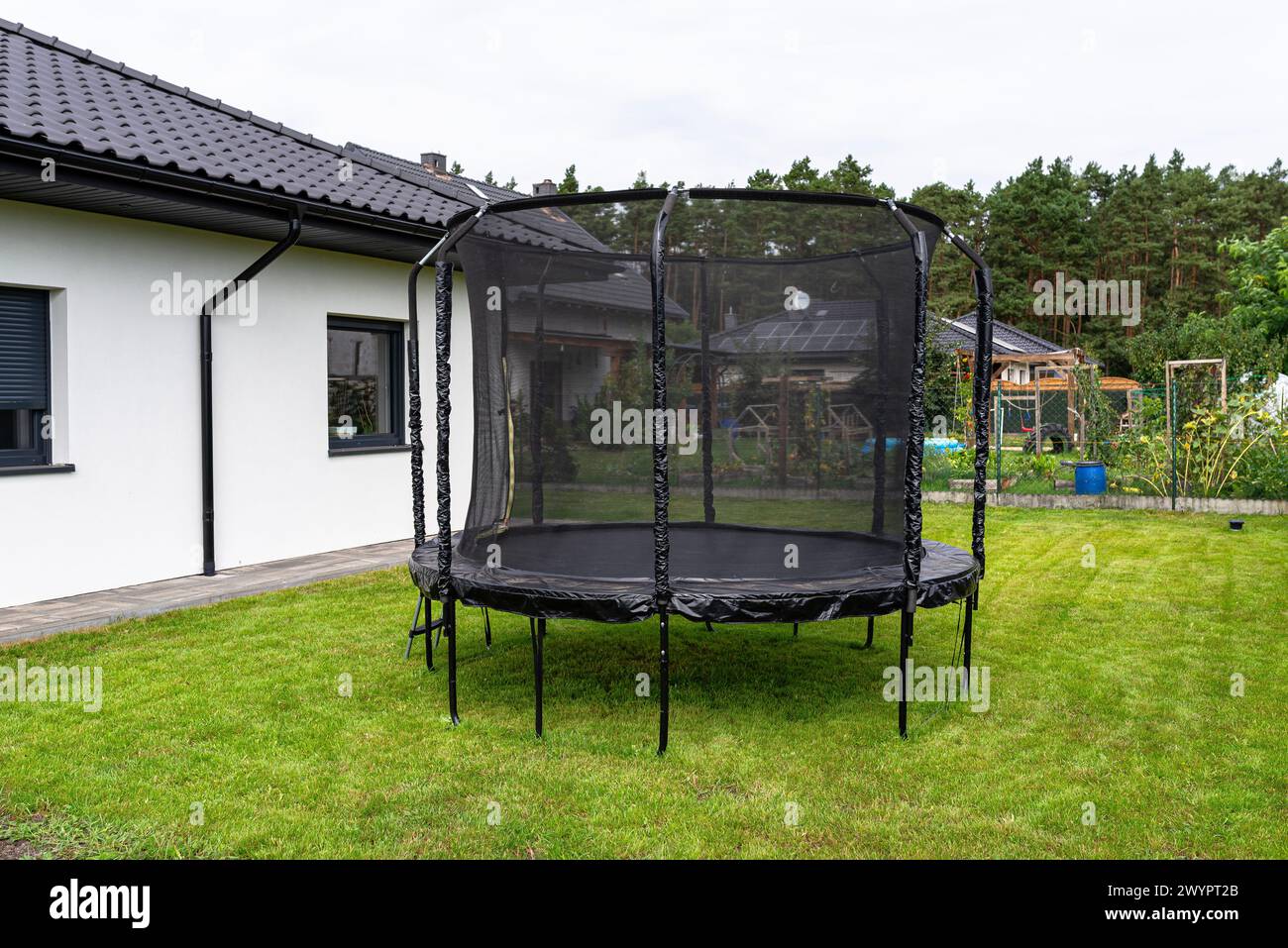Grande trampolino da salto per bambini con rete protettiva e cerniera chiusa, in piedi in giardino. Foto Stock