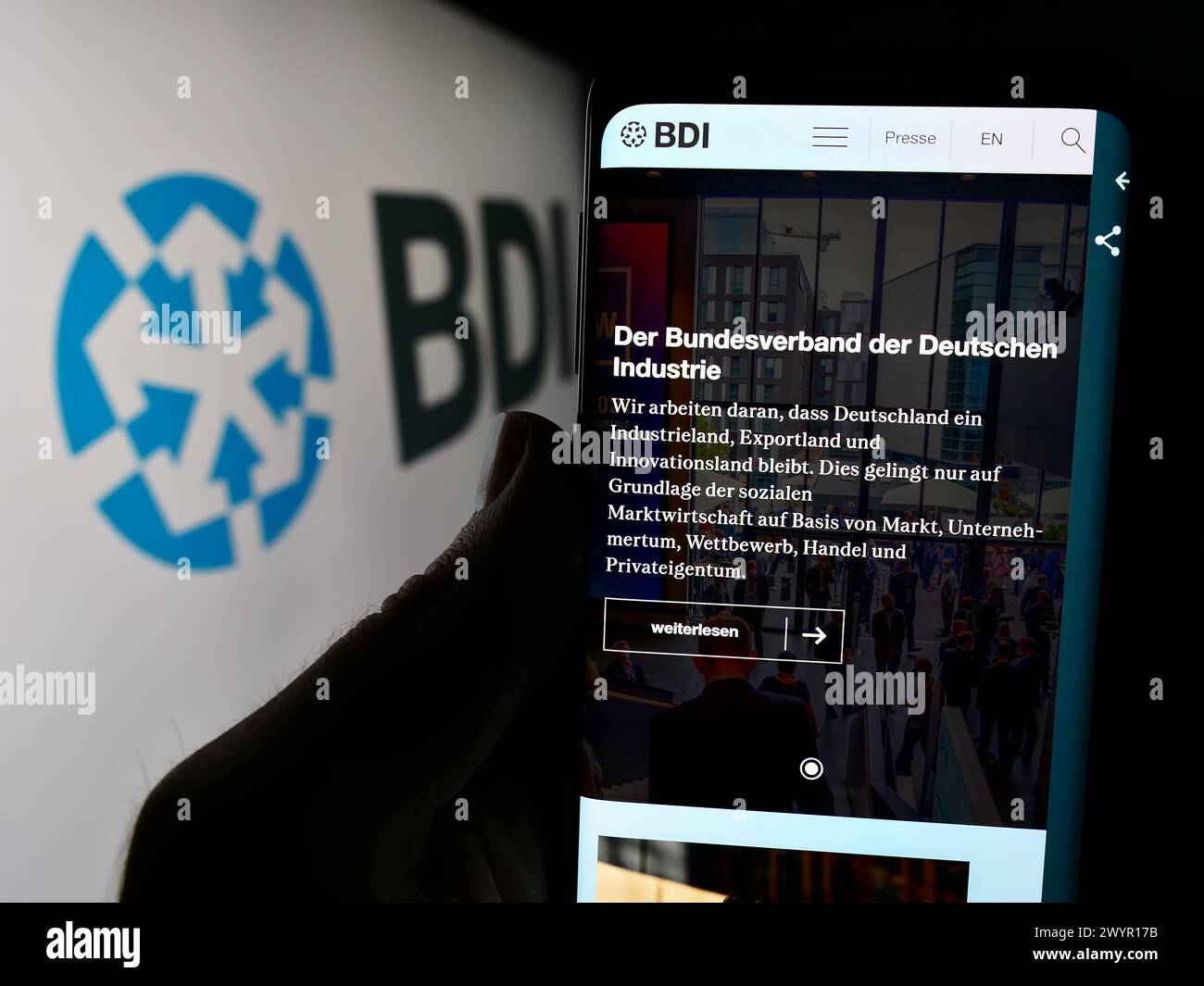 Persona che detiene un cellulare con pagina web della Bundesverband der Deutschen industrie e.V. (BDI) davanti al logo. Messa a fuoco al centro del display del telefono. Foto Stock