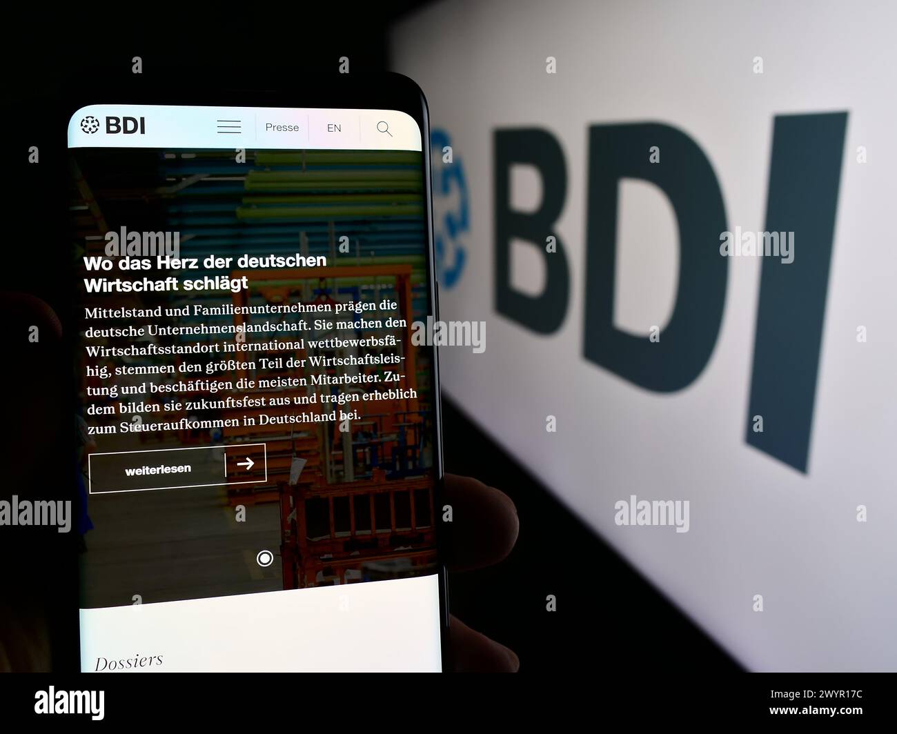 Persona che possiede un telefono cellulare con la pagina Web della Bundesverband der Deutschen industrie e.V. (BDI) davanti al logo. Messa a fuoco al centro del display del telefono. Foto Stock