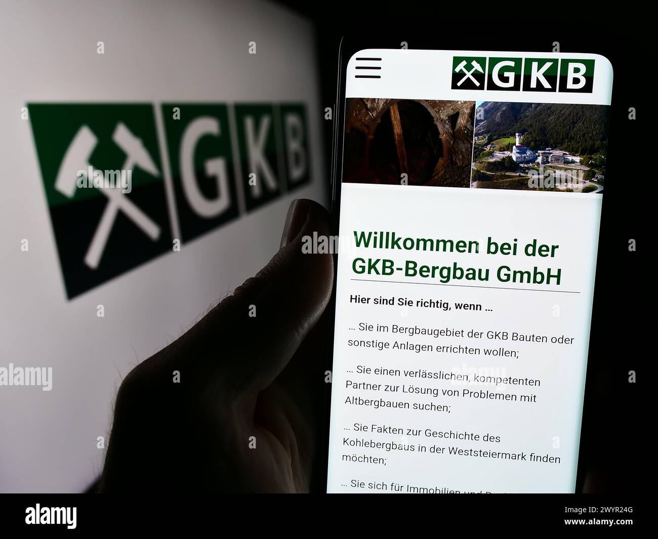 Persona che detiene lo smartphone con il sito web dell'azienda austriaca GKB Bergbau GmbH davanti al logo. Messa a fuoco al centro del display del telefono. Foto Stock