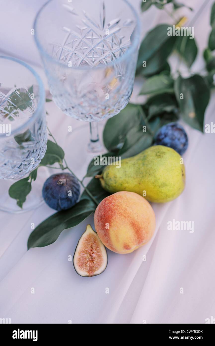 Decorazioni con frutta fresca e bicchieri di cristallo su un elegante tavolo Foto Stock