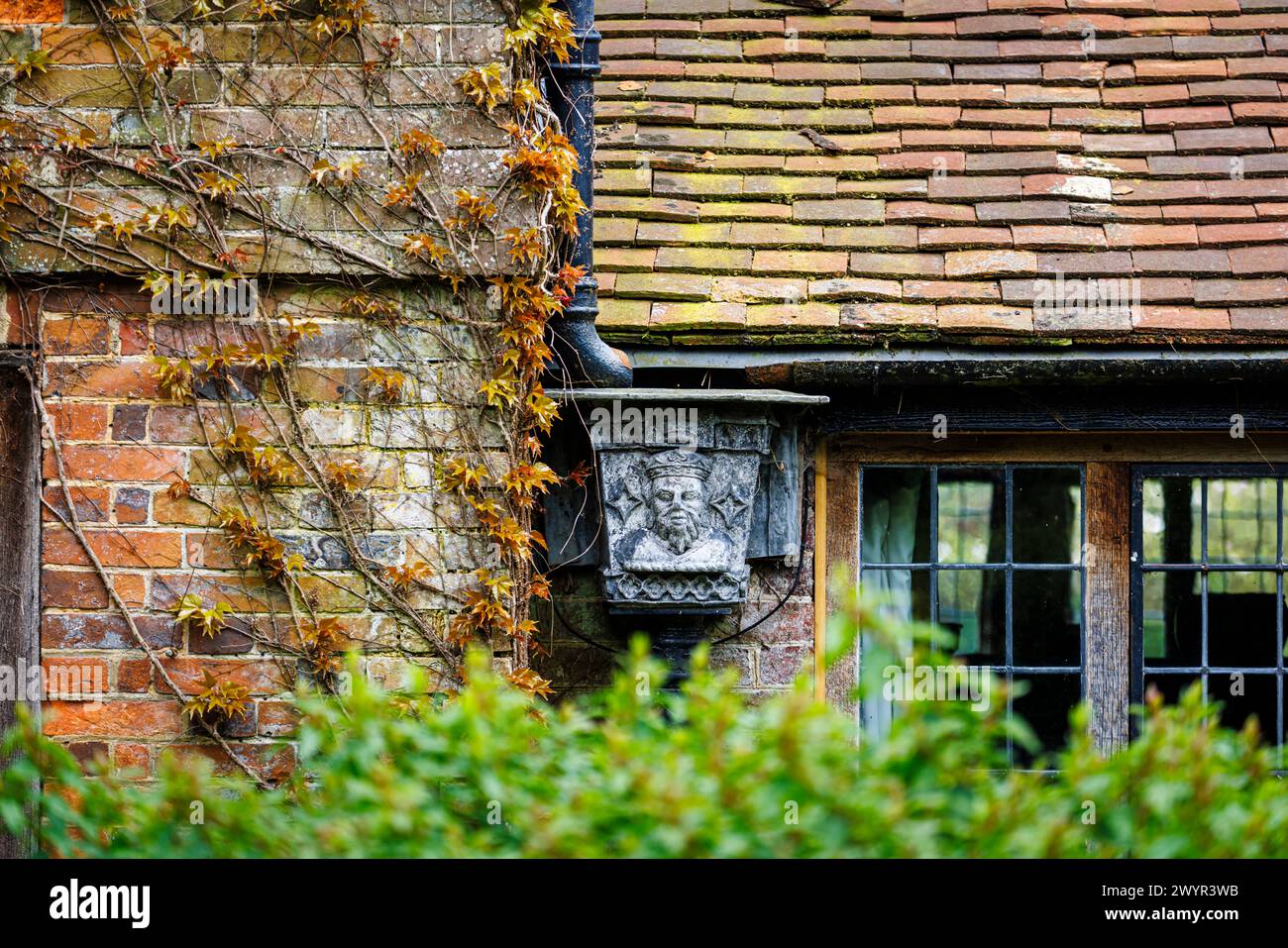 Una tramoggia di metallo vintage con il ritratto di un re incoronato nel sistema grondaiante di Vann House vicino Hambledon, Surrey all'inizio della primavera Foto Stock