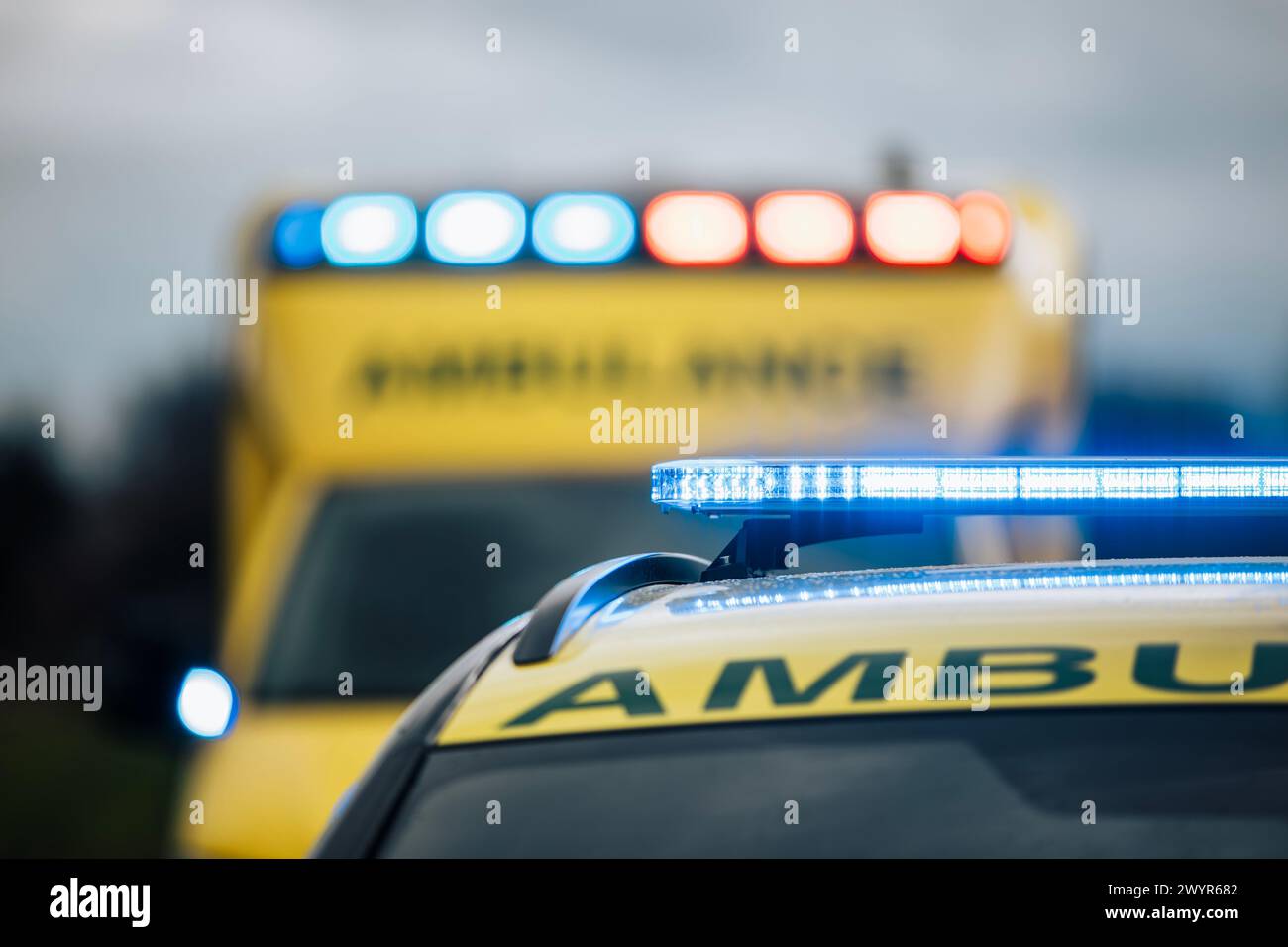 Primo piano del lampeggiatore di luce blu sul tetto di ambulanza auto di servizio medico di emergenza su strada. Temi salvataggio, urgenza e assistenza sanitaria. Foto Stock