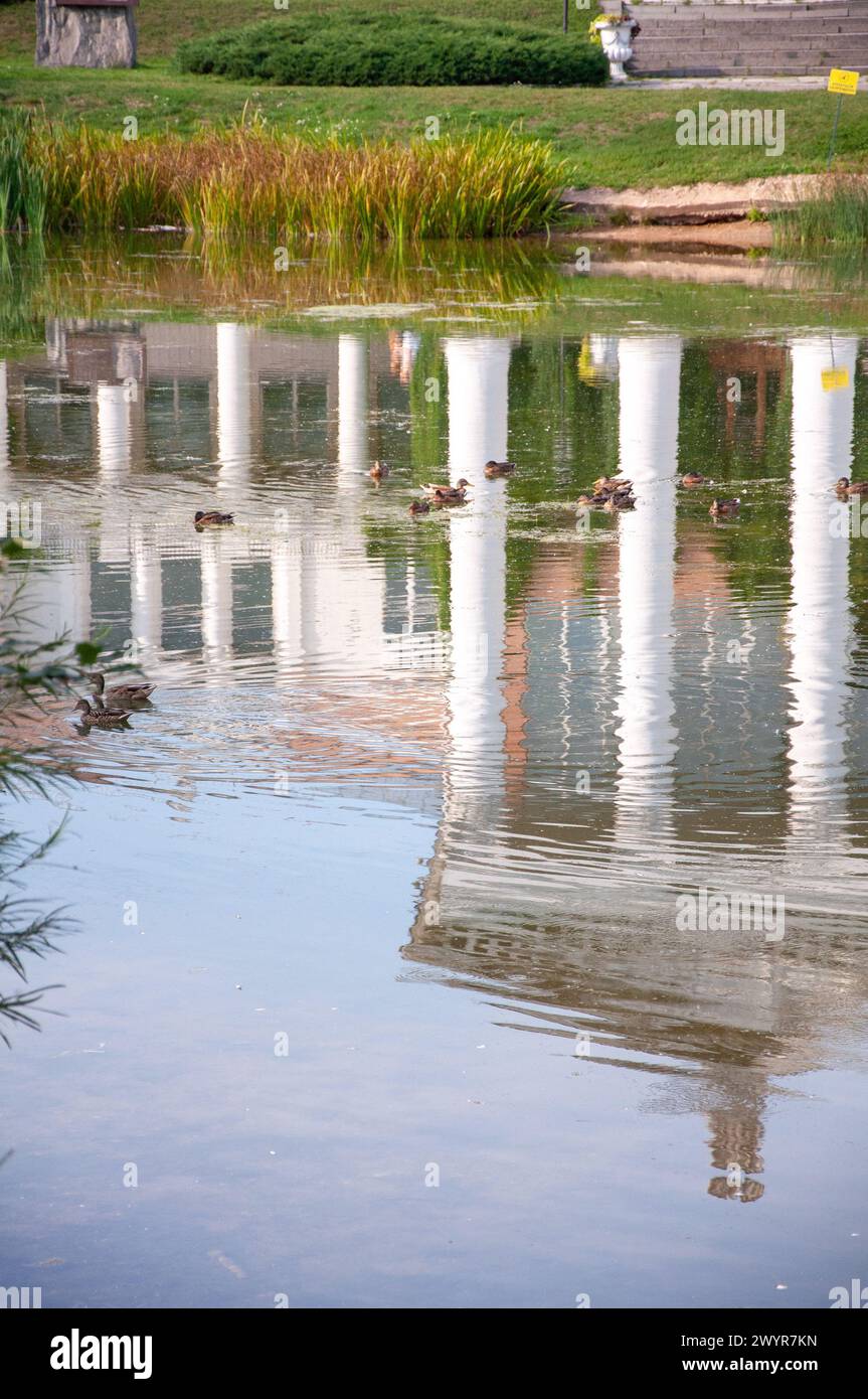 Riflessi di edifici storici nelle acque calme dello stagno. L'architettura antica si riflette nell'acqua del fiume. Concetto di passaggio del tempo. Foto Stock