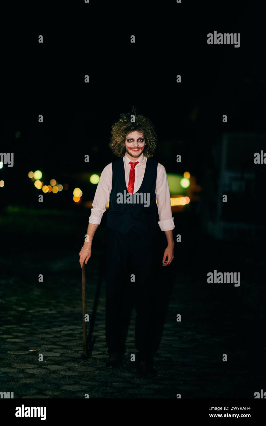 Una figura misteriosa, travestita da assassino in una tuta dai capelli selvatici, brandisce un'ascia minacciosa, incarnando l'essenza stessa della paura e del pericolo Foto Stock