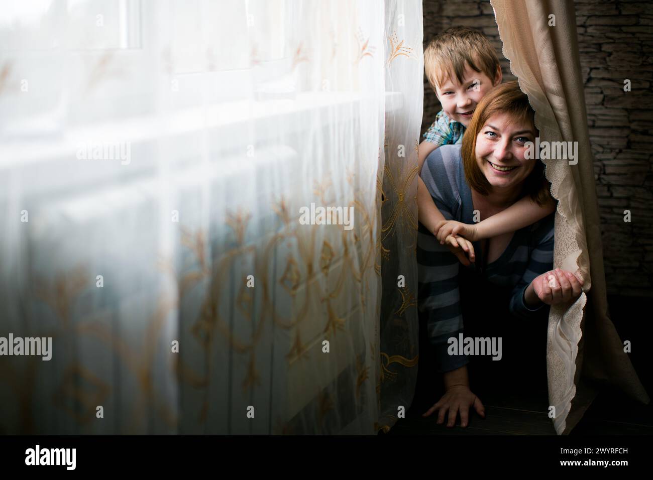 Mamma felice e il suo bambino giocano in una stanza accogliente. Foto Stock