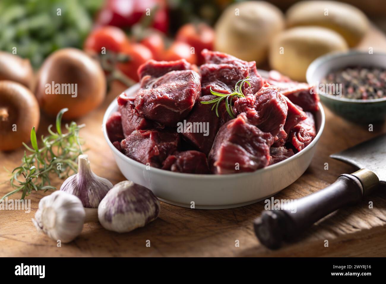 Pezzi di manzo tritato in un recipiente con verdure, pronti per il gulasch. Foto Stock