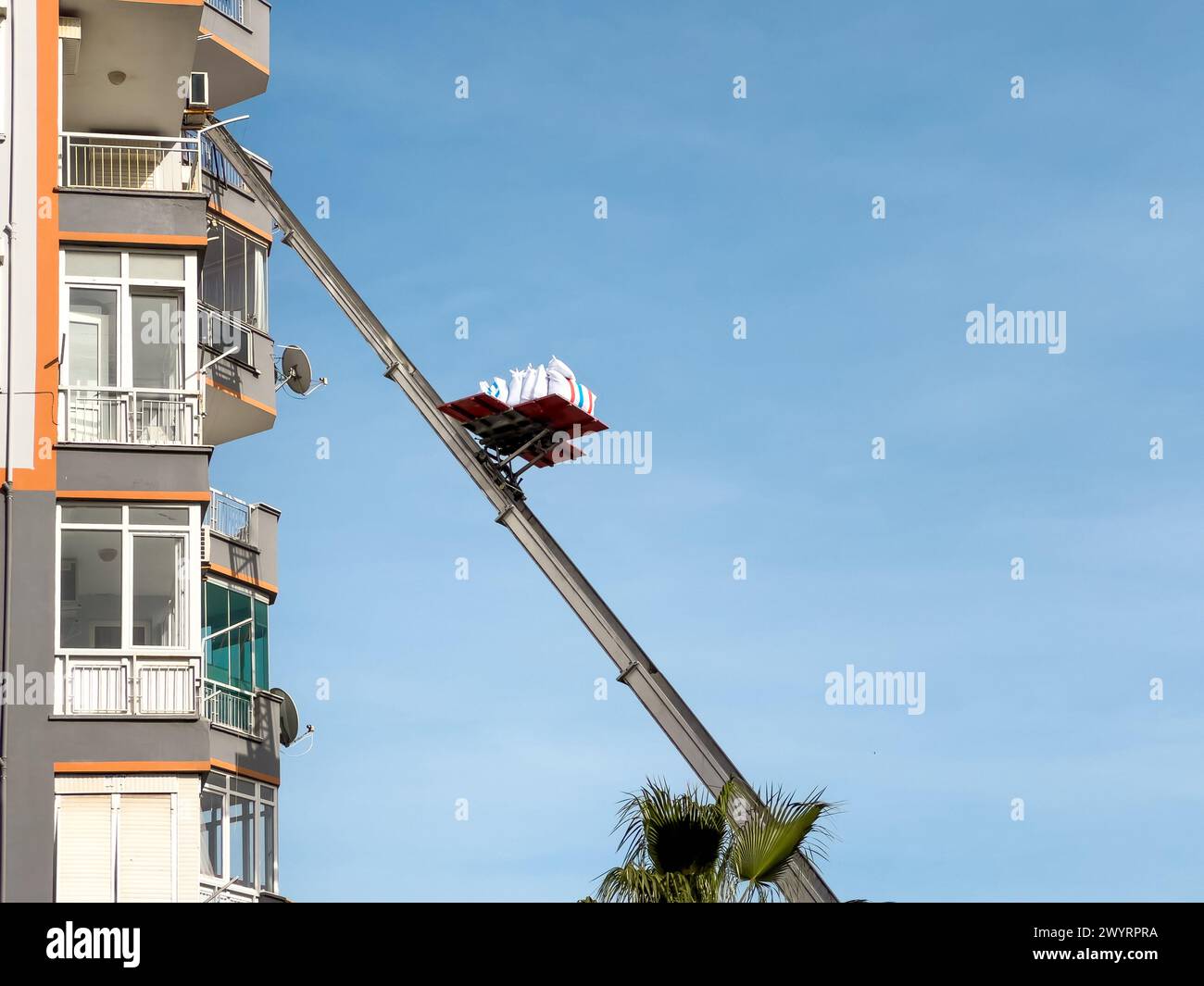 Rimozione iniziale con sollevatore idraulico. Trasportatori che trasportano merci in ascensore dalla finestra dell'edificio Foto Stock