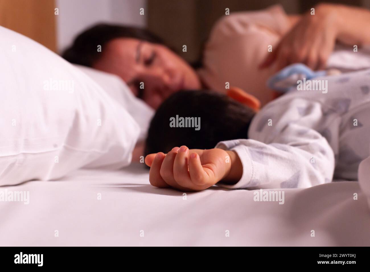 Mamma stanca con il bambino che dorme a letto fuori fuoco Foto Stock