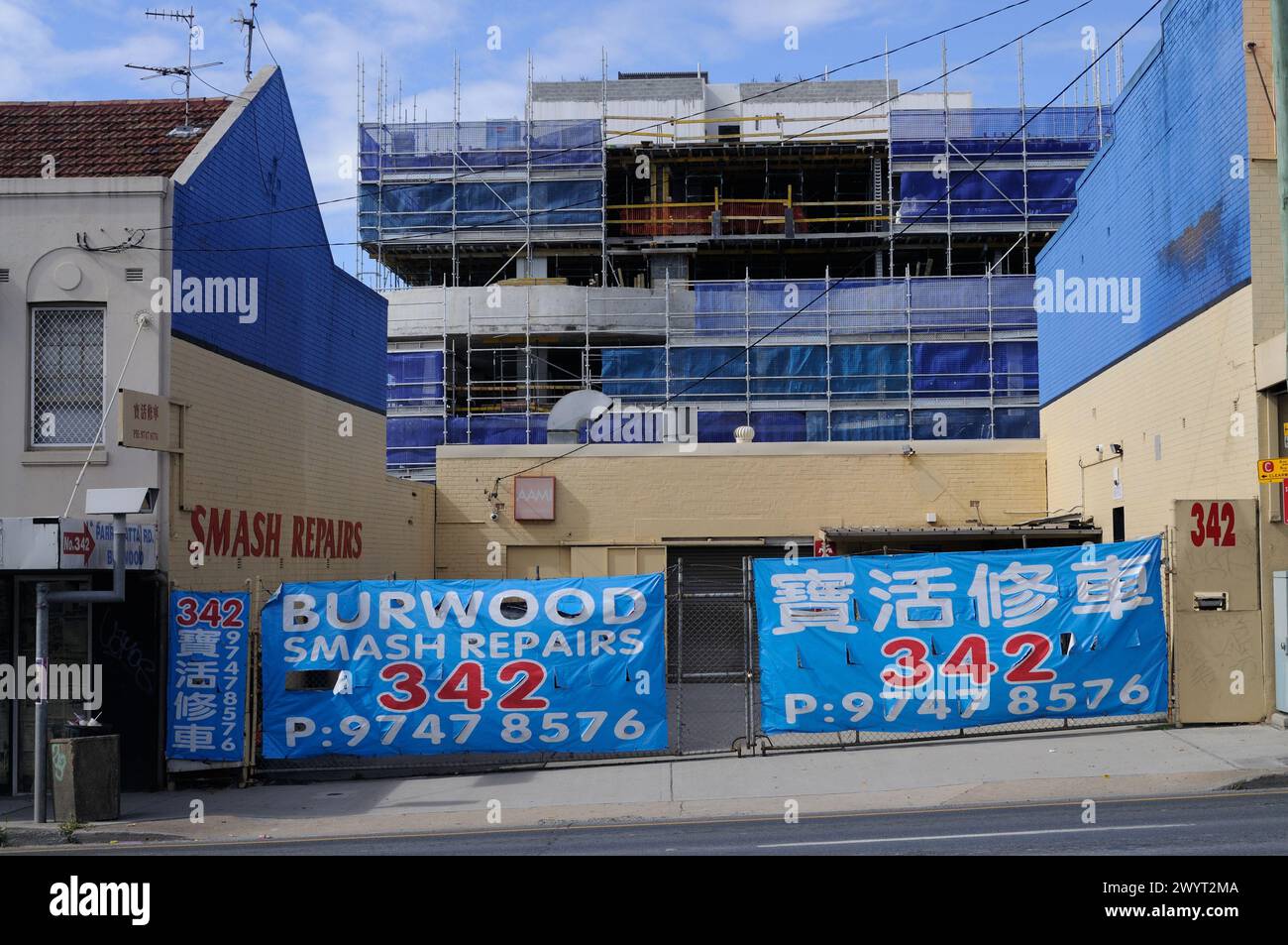 Striscioni blu per riparazioni Burwood Smash alle porte di un deposito auto vuoto in Paramatta Rd Burwood , e nuovi appartamenti in costruzione Foto Stock