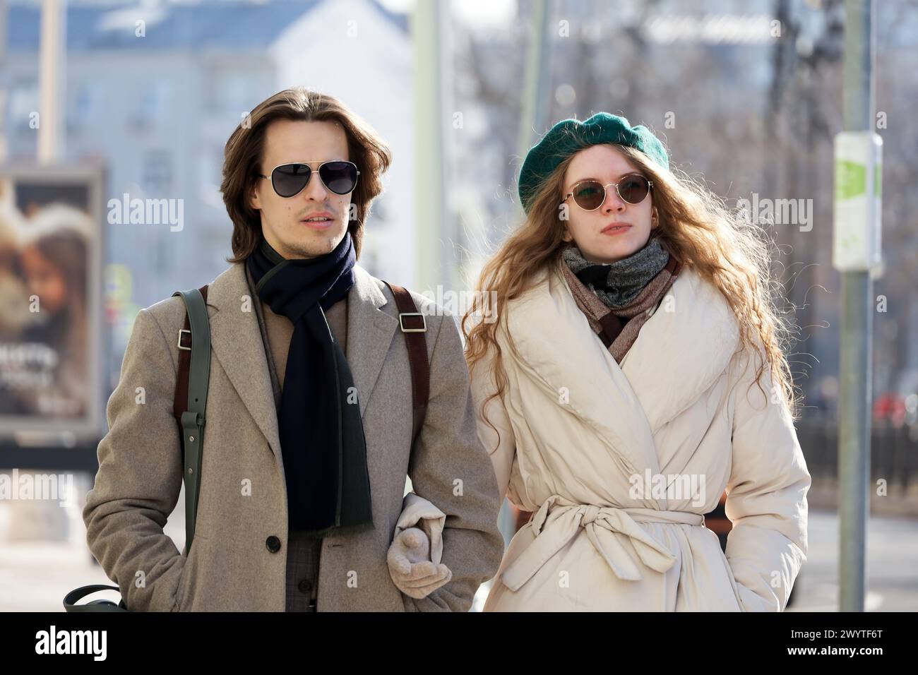 Giovane coppia elegante con occhiali da sole che cammina per la strada della città tenendosi per mano, moda nella stagione primaverile Foto Stock