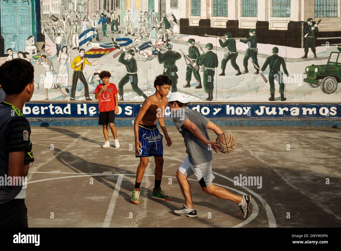 Partita di pallacanestro davanti a murales raffiguranti la storia di León, León, dipartimento di León, Nicaragua, America centrale Foto Stock