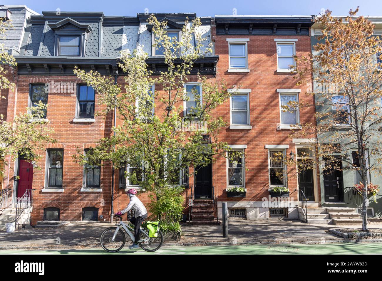 Ciclista di fronte alle case di fila, quartiere di Fitlers Square, Philadelphia, Pennsylvania, Stati Uniti Foto Stock