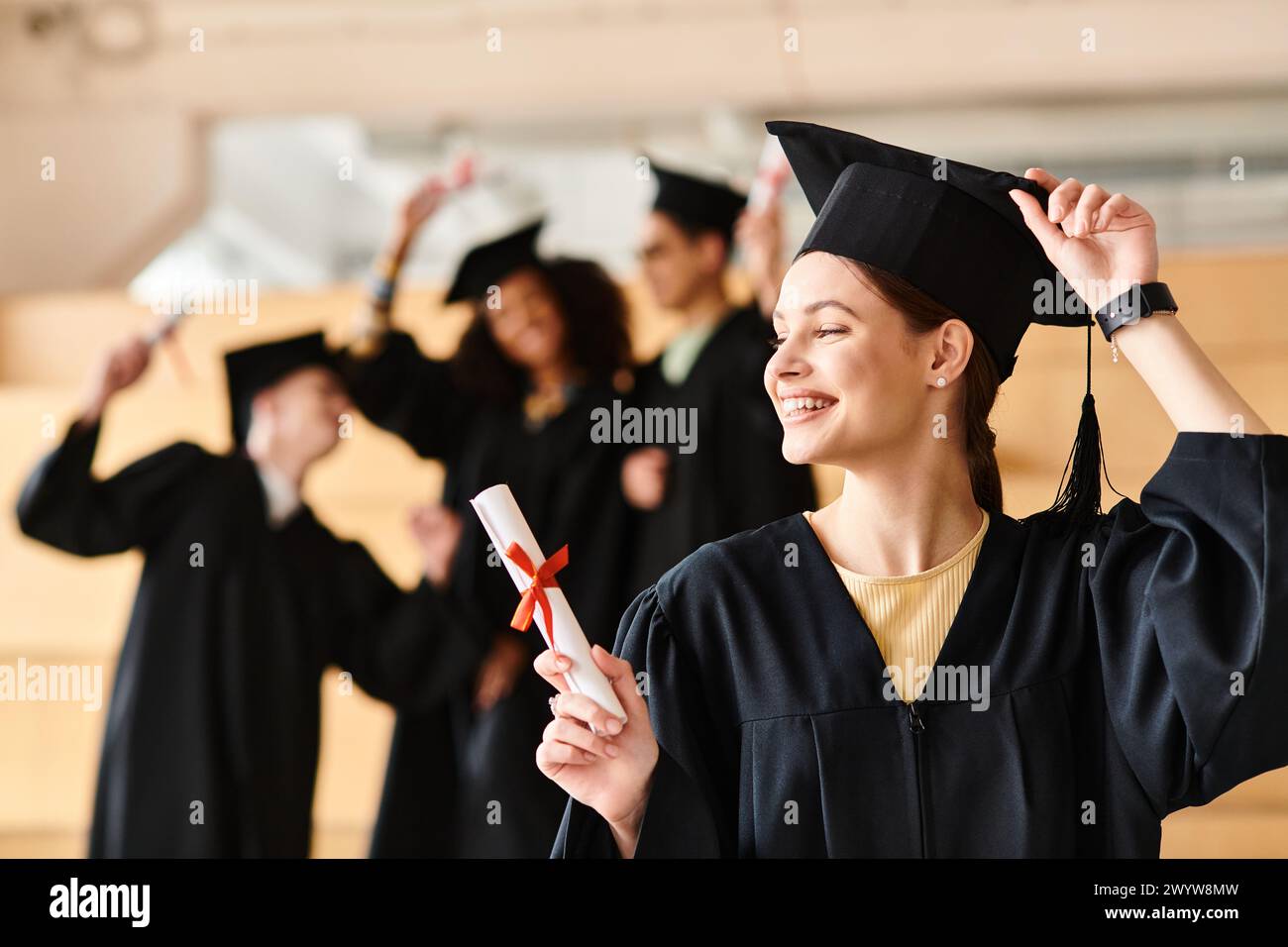 Donna di diversa eredità detiene con orgoglio il diploma di laurea in abito e berretto. Foto Stock