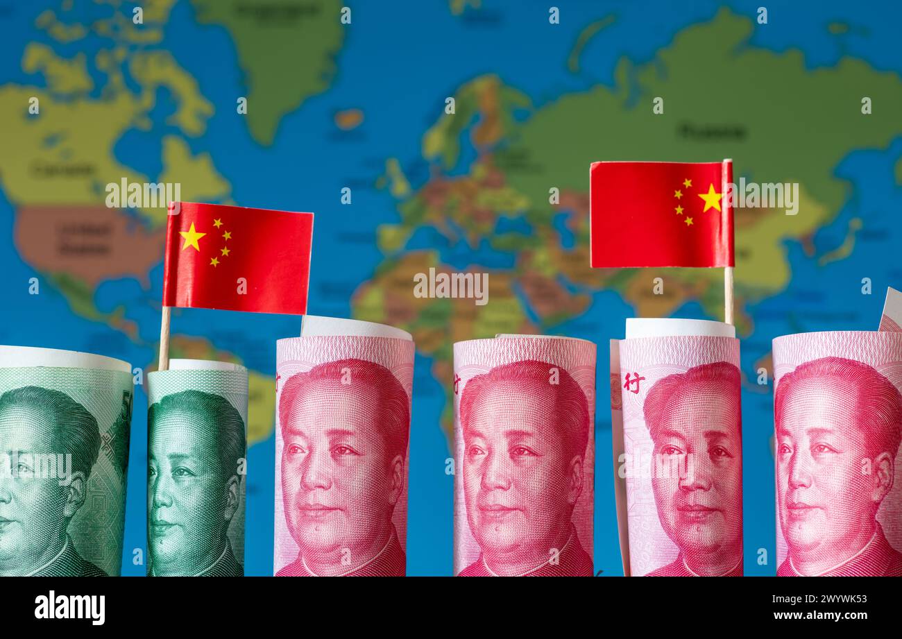 Un concetto di investimento cinese a livello mondiale, Belt and Road Initiative, con rotoli di yuan cinese e bandiere nazionali su una mappa del mondo. Foto Stock