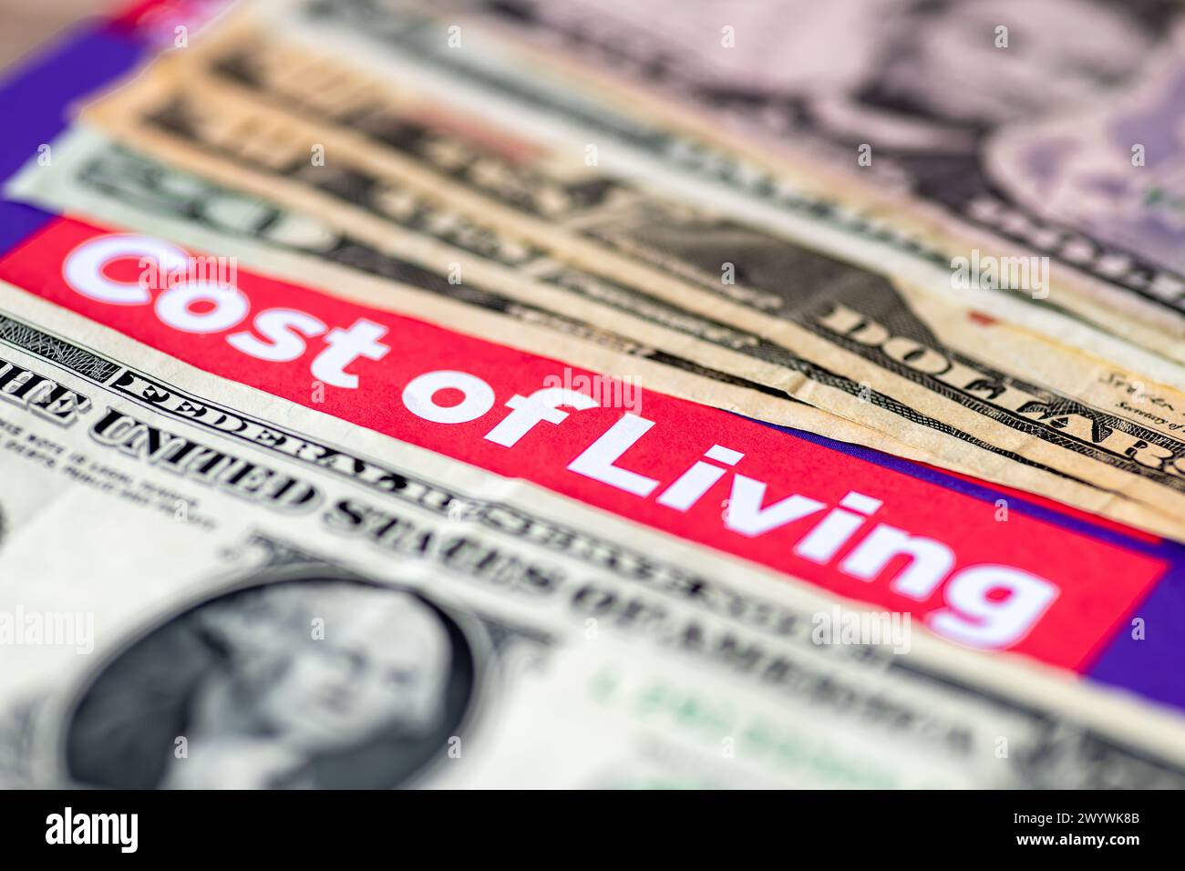 Un macro primo piano di banconote in dollari USA e le parole costo della vita. Un concetto di costo della vita e inflazione. Foto Stock