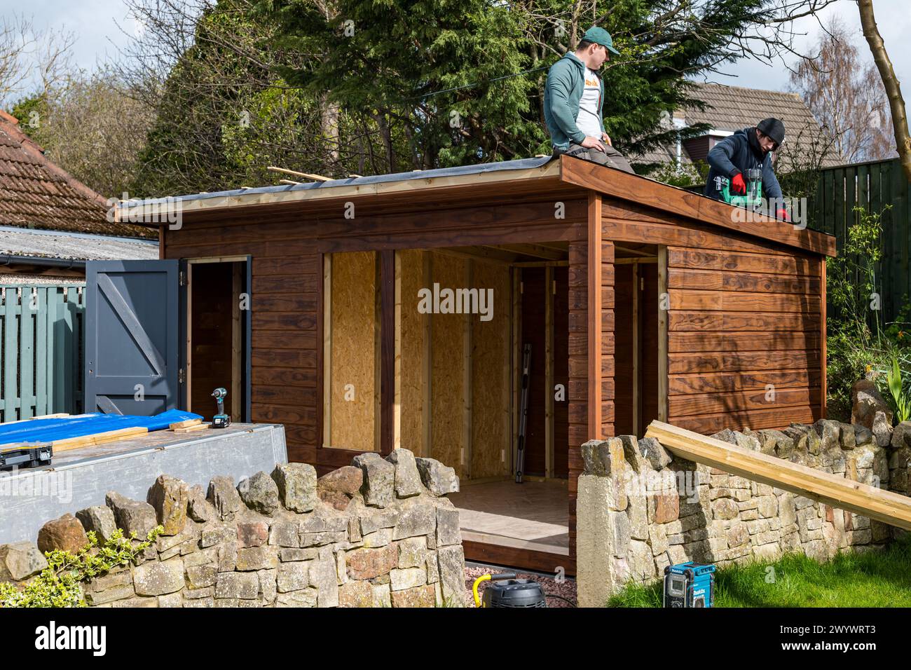 Falegnami e operai che montano un tetto per costruire un capannone e un giardino, Scozia, Regno Unito Foto Stock