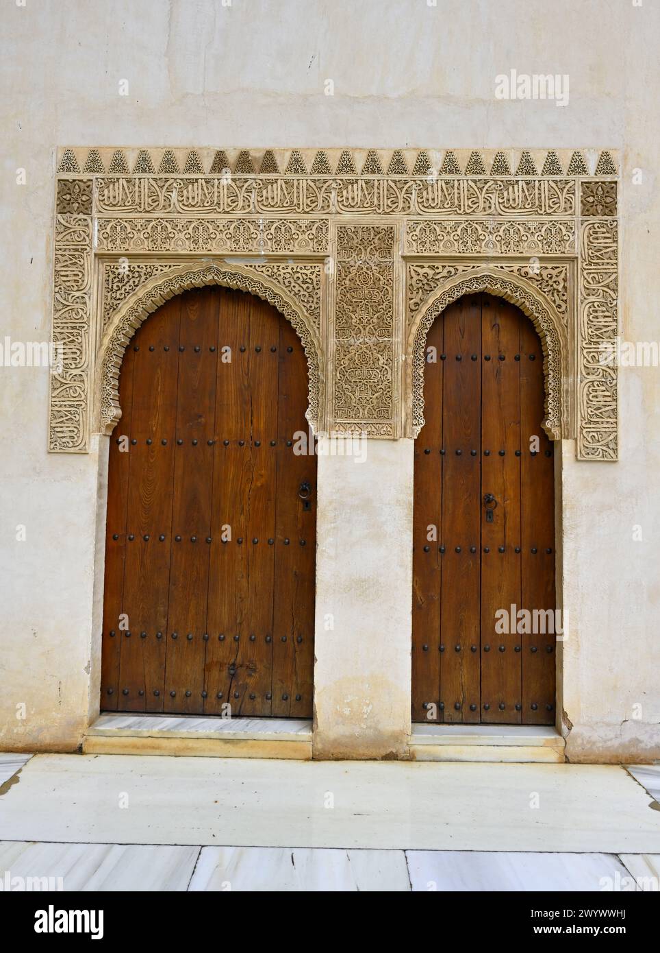 Elaborati intonaci in stile moresco e due porte ad arco in legno all'interno della Corte dei mirtilli, dei Palazzi Nasridi, del Palazzo dell'Alhambra, Granada, Spagna Foto Stock