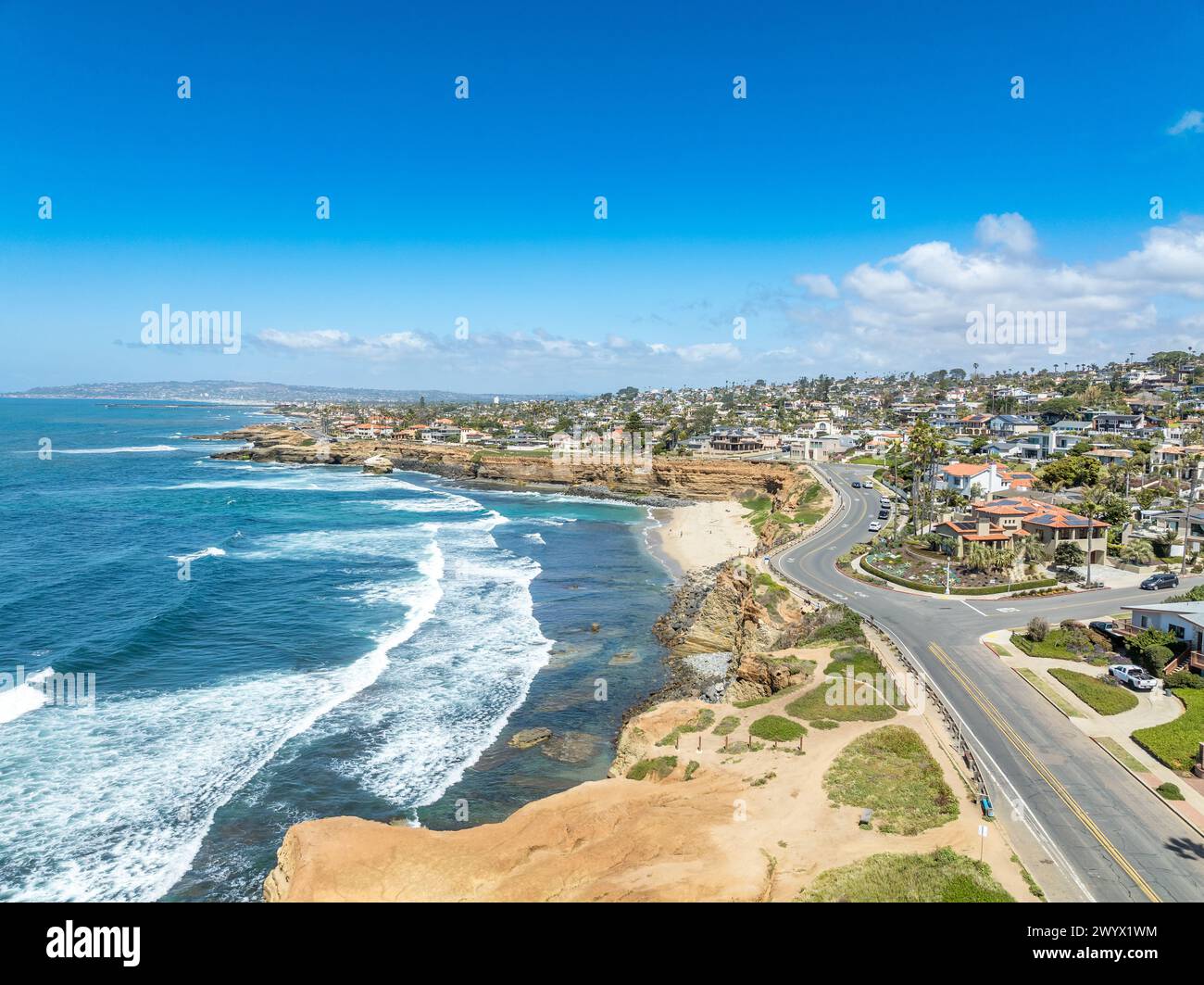 Panorama aereo di Sunset Beach a San Diego con la costa frastagliata dell'oceano californiano, onde schiaccianti, lussuose case per famiglie singole e residenze con po Foto Stock