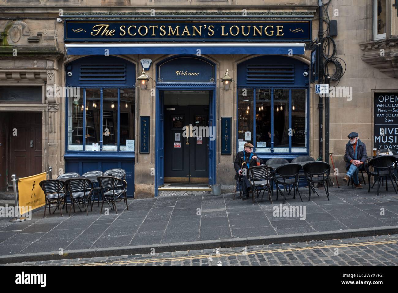 Due anziani seduti fuori dalla casa pubblica Scotsman's Lounge in Cockburn Street, nella città vecchia di Edimburgo. Foto Stock