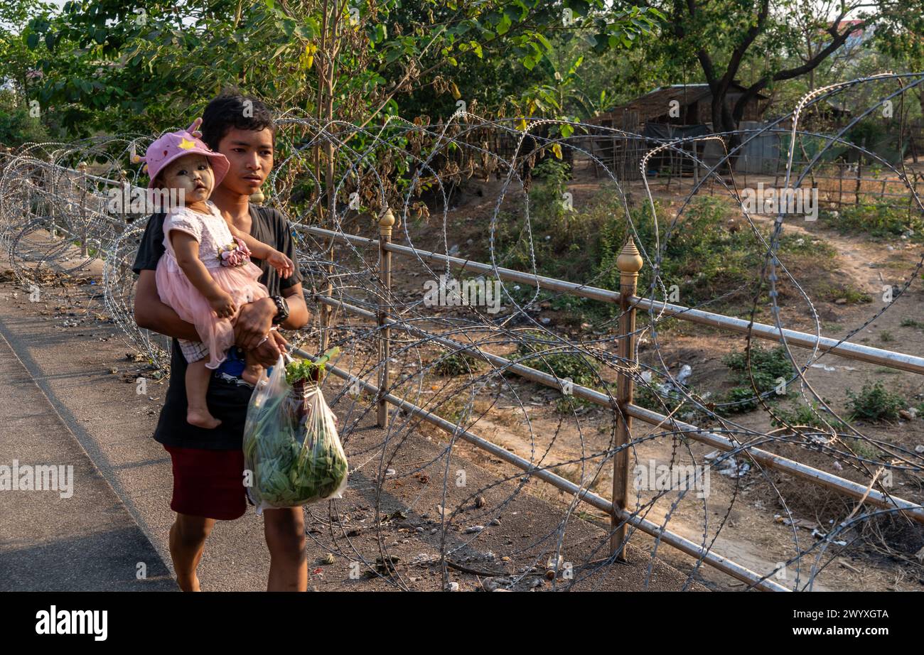 Visitatori, commercianti e immigrati birmani illegali camminano su filo spinato sul lato thailandese del confine tra Thailandia e Myanmar a Mae Sot, Thailandia. Foto Stock