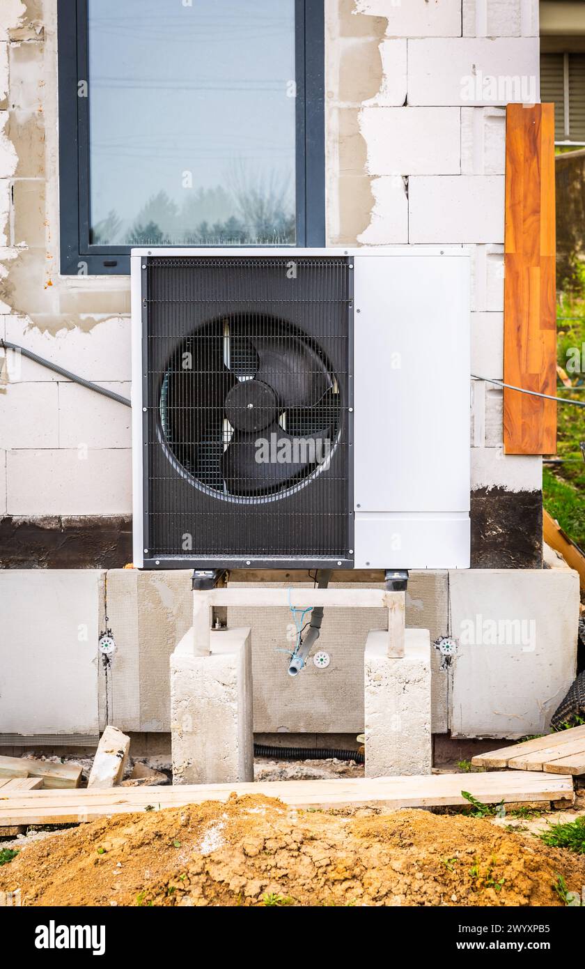Pompa di calore a sorgente d'aria installata all'esterno di una nuova e moderna casa in costruzione, concetto di energia rinnovabile verde della pompa di calore Foto Stock