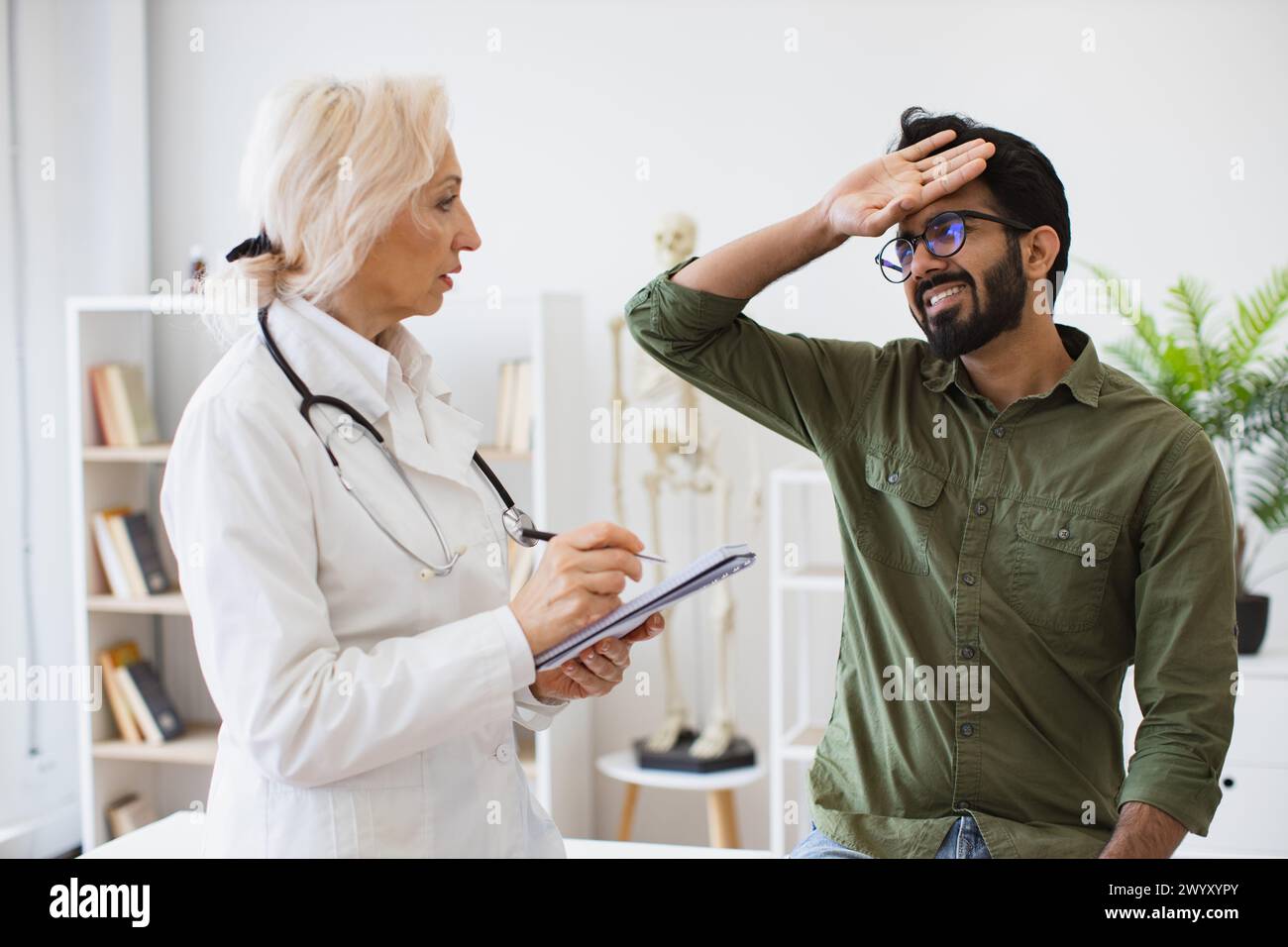Medico anziano che fornisce raccomandazioni e scrive prescrizione. Foto Stock