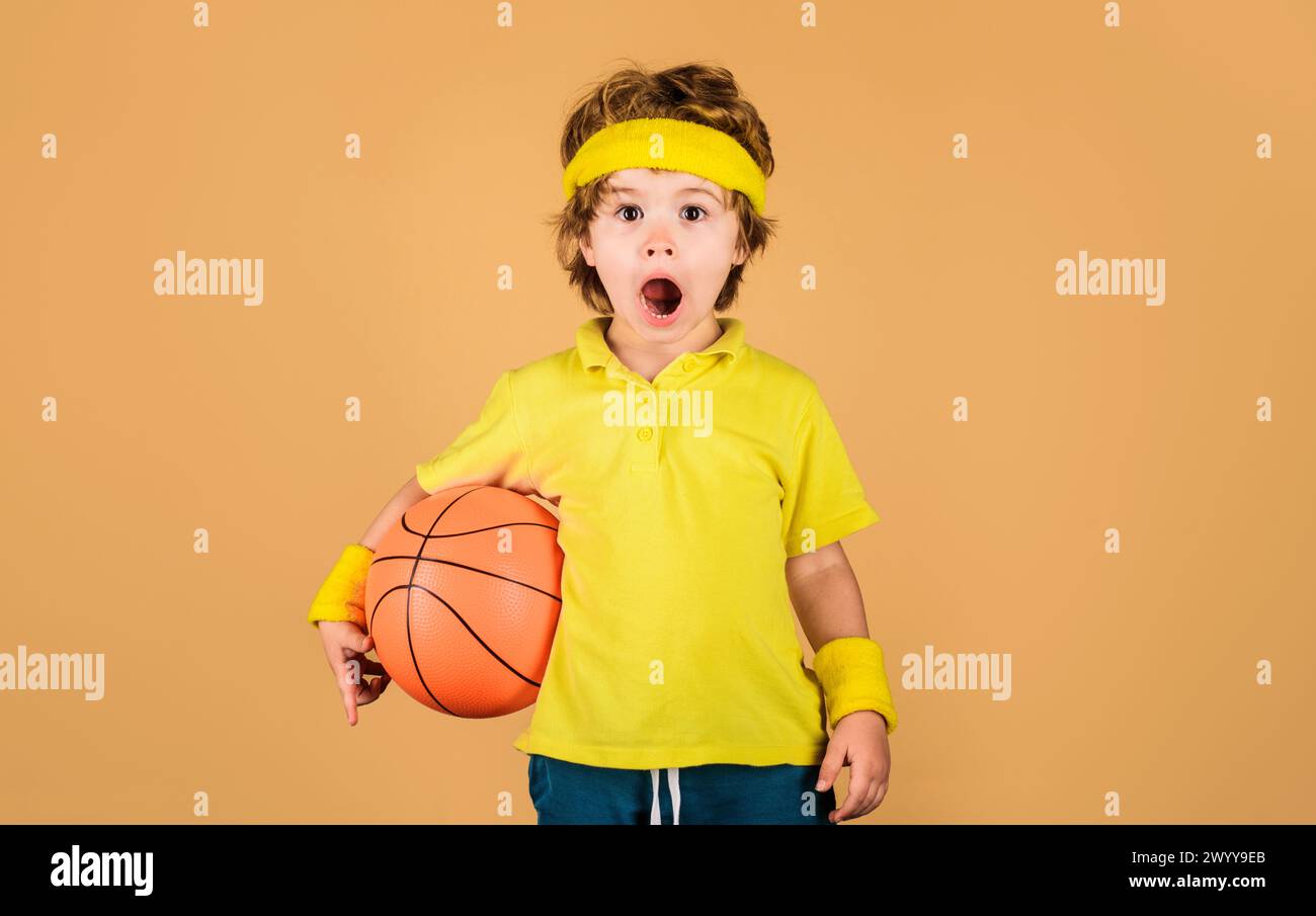 Sport per bambini. Ha sorpreso il giocatore di basket con un abbigliamento sportivo con pallone da basket. Fitness, allenamento, stile di vita sano e concetto di hobby Foto Stock