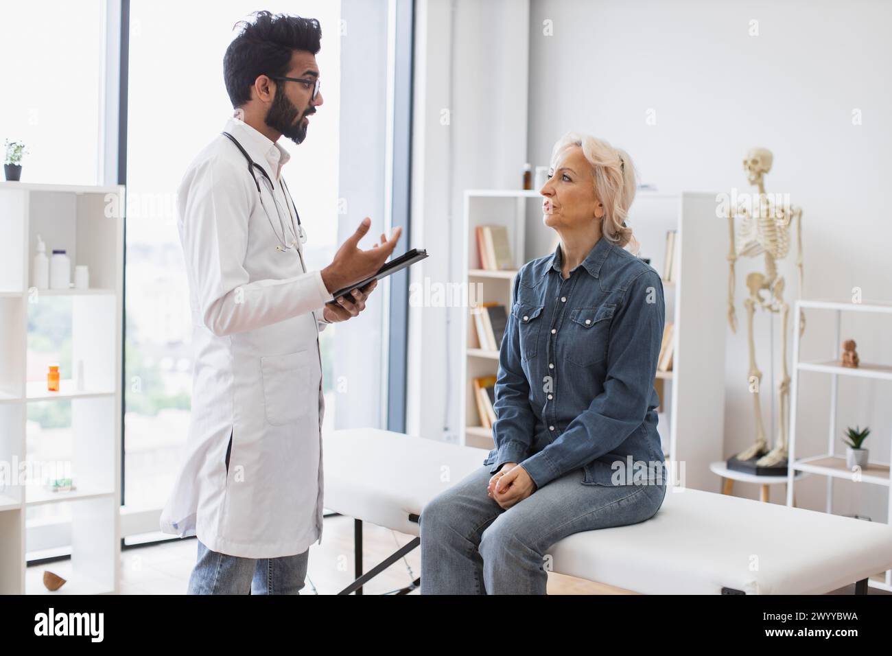 Medico con barba adulta che fornisce consigli e utilizza il tablet. Foto Stock
