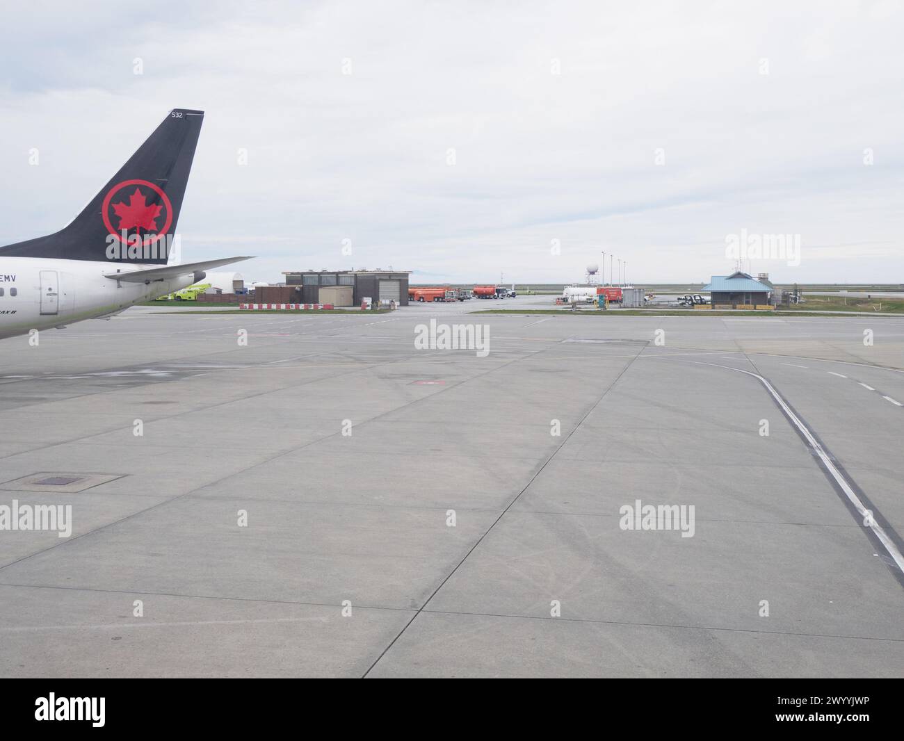 Sezione libera dell'asfalto dell'aeroporto con sezione di coda del jet passeggeri e degli edifici annessi, infrastruttura di comunicazione a distanza. Foto Stock