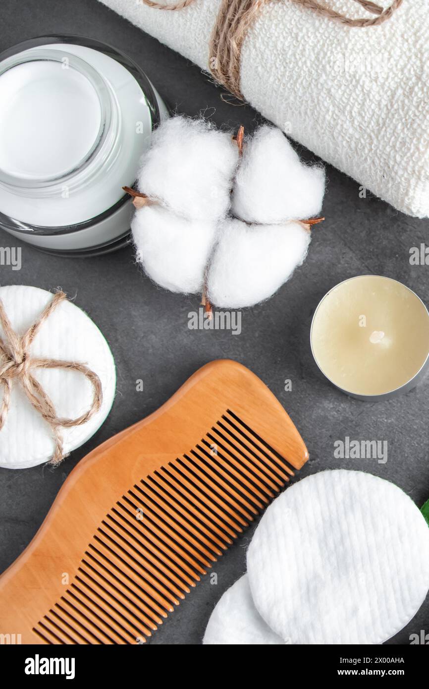 Cosmetici naturali per la cura del corpo su sfondo concreto. Accessori per il centro benessere, asciugamano, spazzola per capelli, olio essenziale. Composizione della disposizione piatta. Prodotti ecologici, Zer Foto Stock