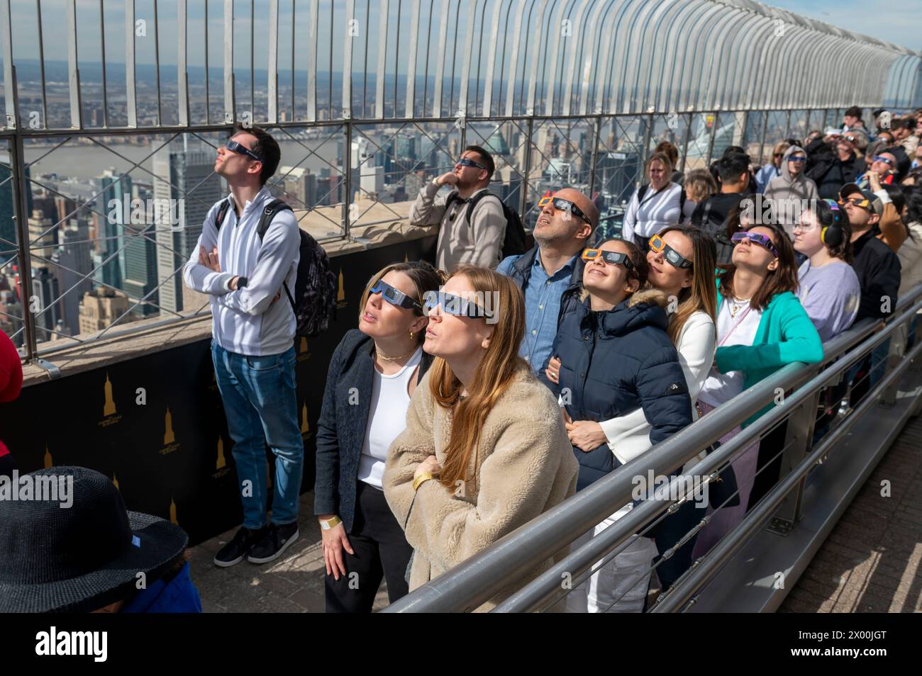 NEW YORK, NEW YORK - 8 APRILE: La gente guarda un'eclissi solare parziale dal ponte di osservazione al 86° piano dell'Empire State Building l'8 aprile 2024 a New York. Con la prima eclissi solare a passare attraverso il Nord America in sette anni, New York non era sulla via della totalità, con solo il 90% del sole coperto dalla luna; la prossima eclissi visibile negli Stati Uniti sarà nel 2044. Foto Stock