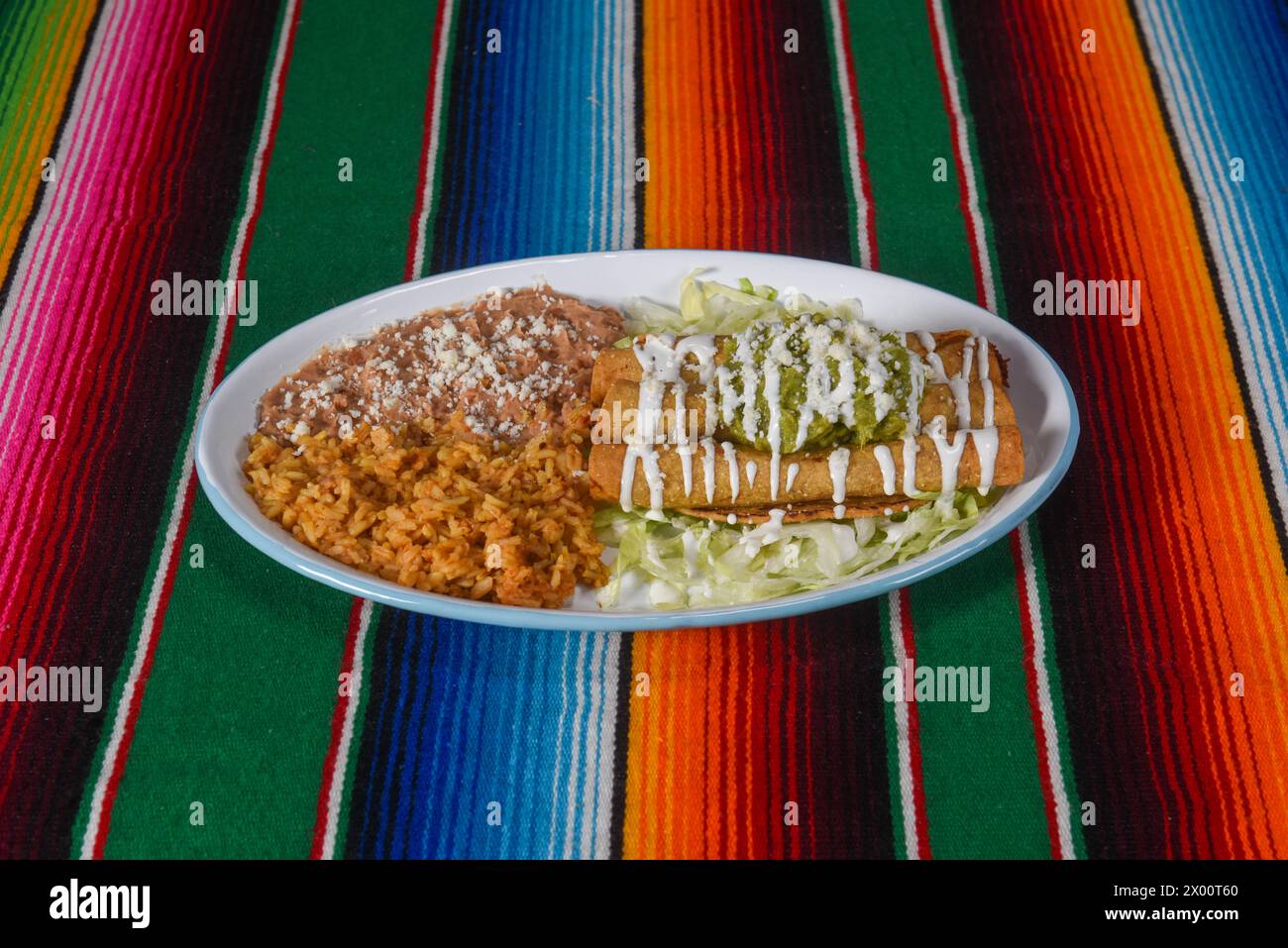 Un delizioso piatto di taquito fritto dorato con un lato di riso spagnolo e fagioli fritti. Foto Stock