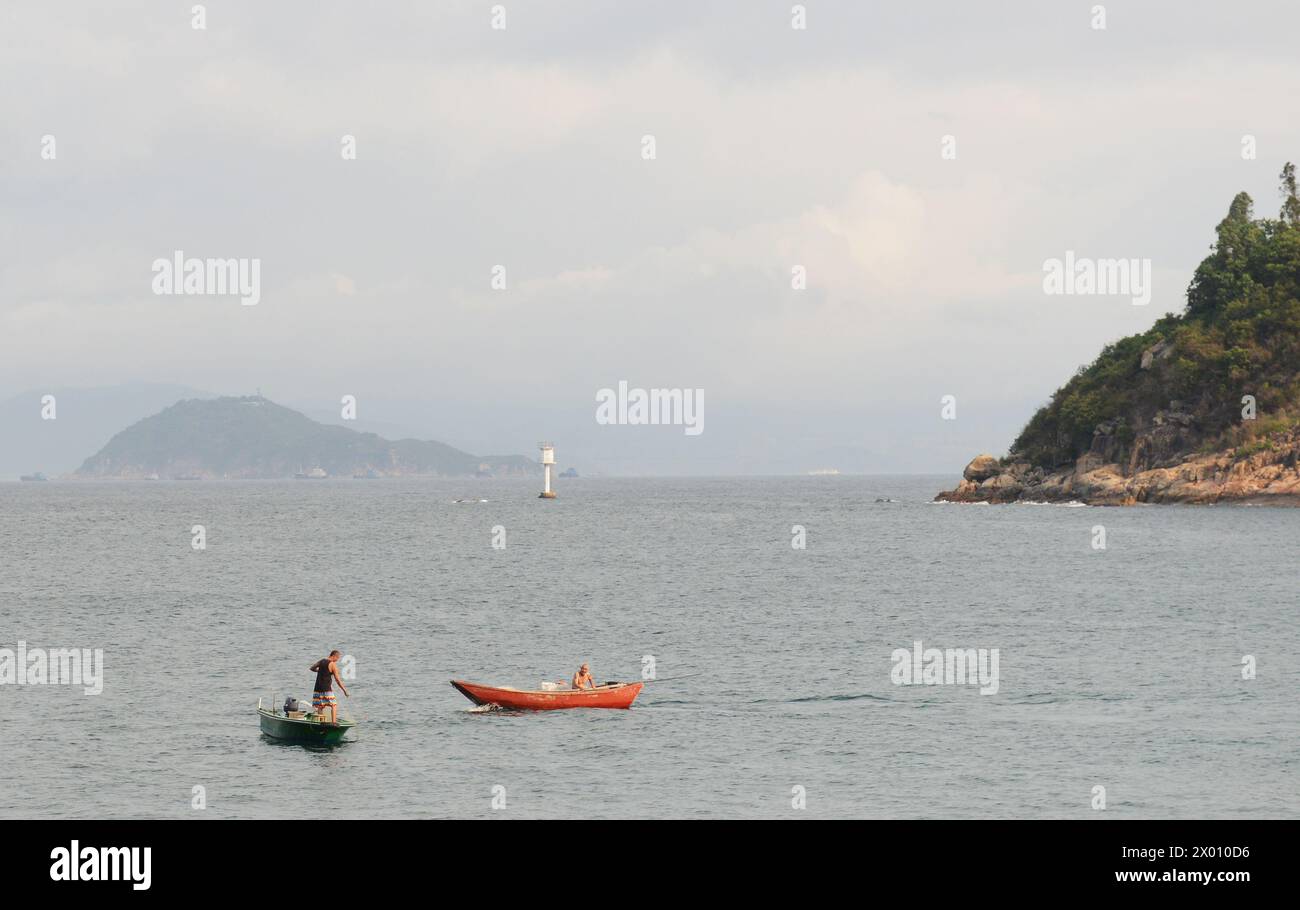 Un pescatore cinese che pesca dalla sua barca al largo della costa dell'isola di Lamma a Hong Kong. Foto Stock