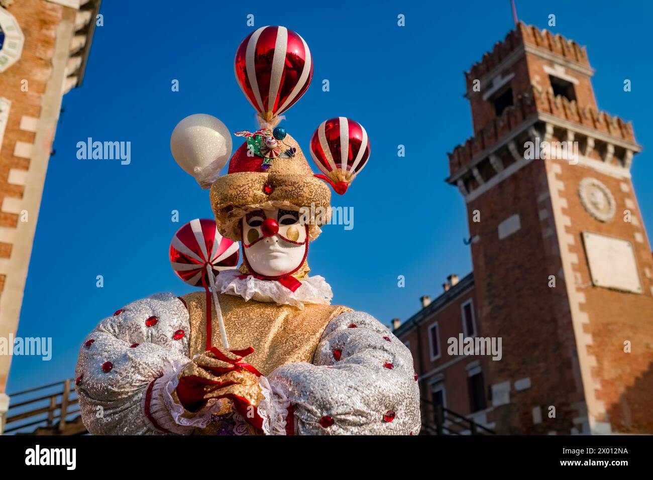 Ritratto di una persona mascherata in costume creativo, in posa presso gli edifici dell'Arsenale, celebrando il Carnevale veneziano. Foto Stock