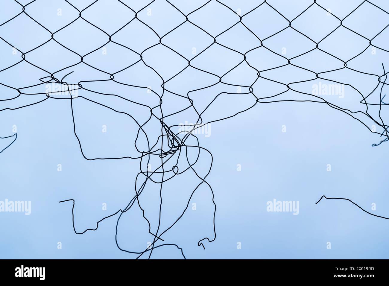 Rottura della recinzione a maglie a catena contro il cielo invernale coperto, concetto di libertà. Messa a fuoco selettiva. Foto Stock