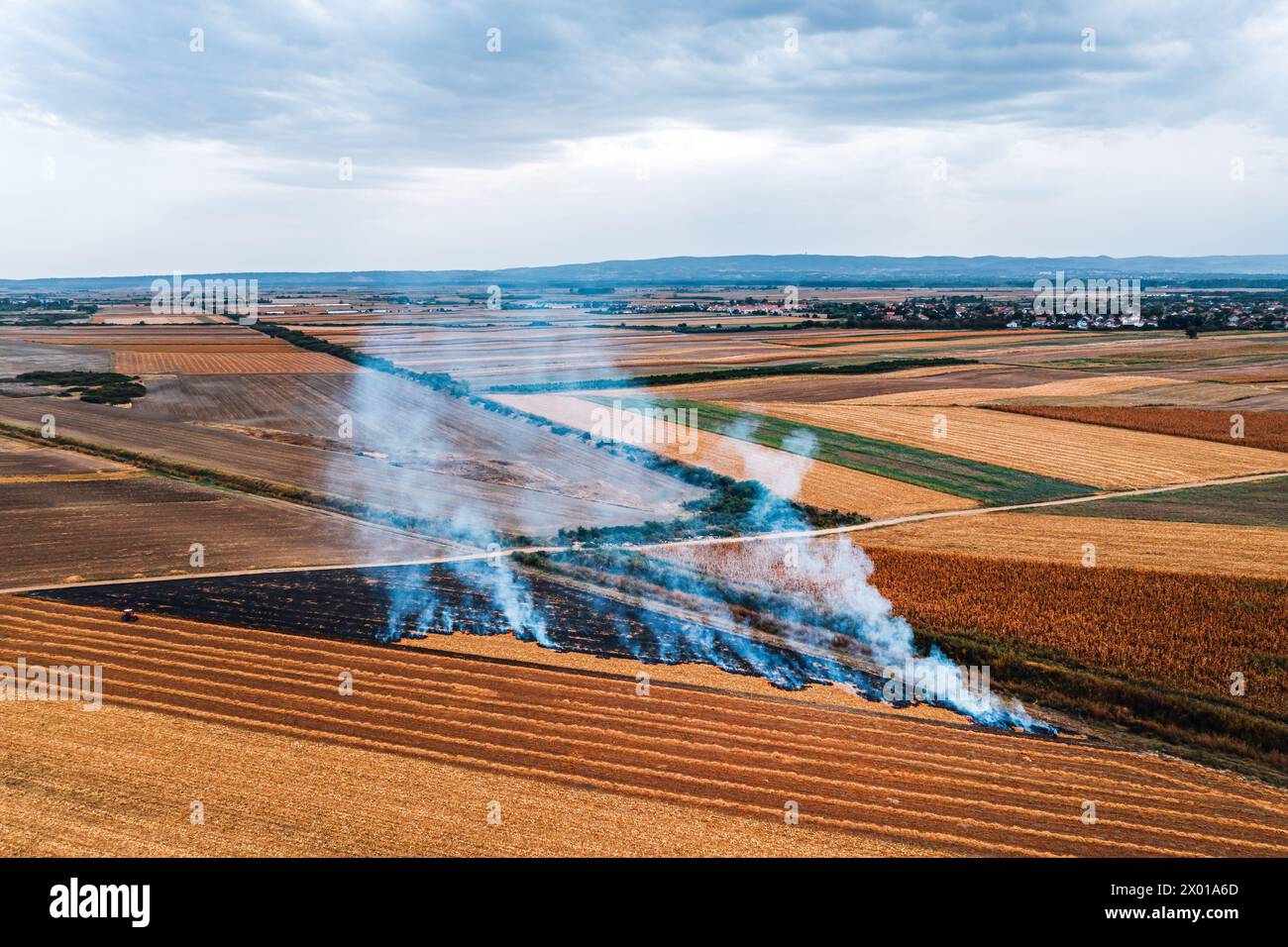 La combustione delle stoppie del campo di grano dopo la raccolta dei cereali è una delle principali cause di inquinamento atmosferico, colpo aereo dal drone pov, visuale dall'alto Foto Stock